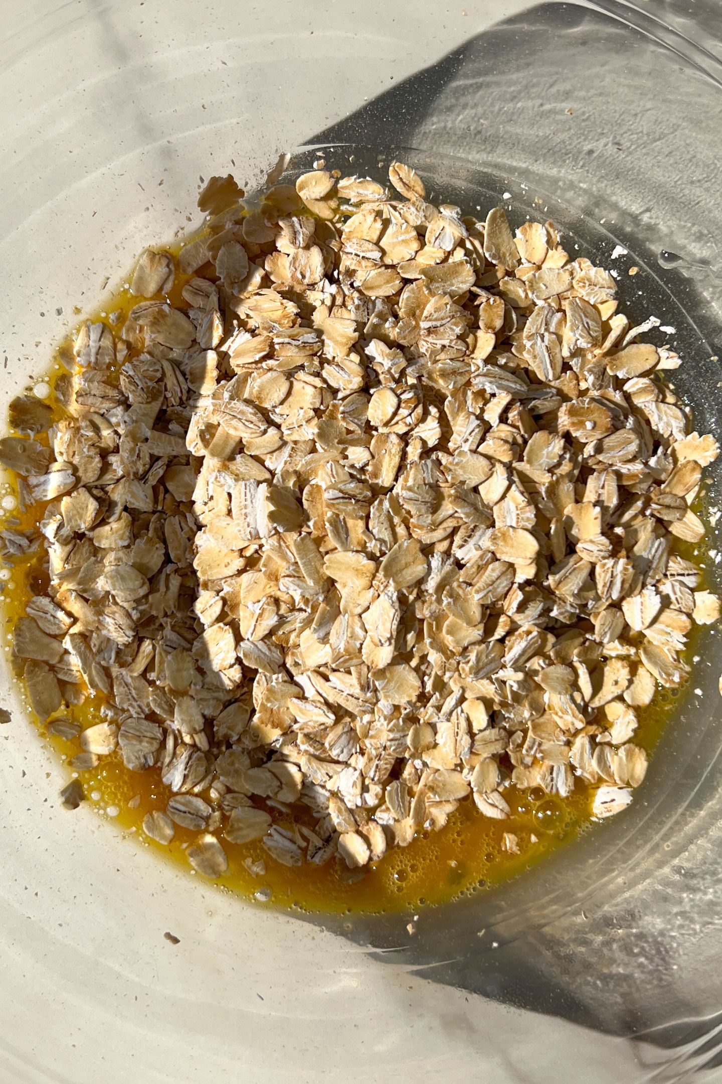 Liquid ingredients in a mixing bowl with rolled oats.