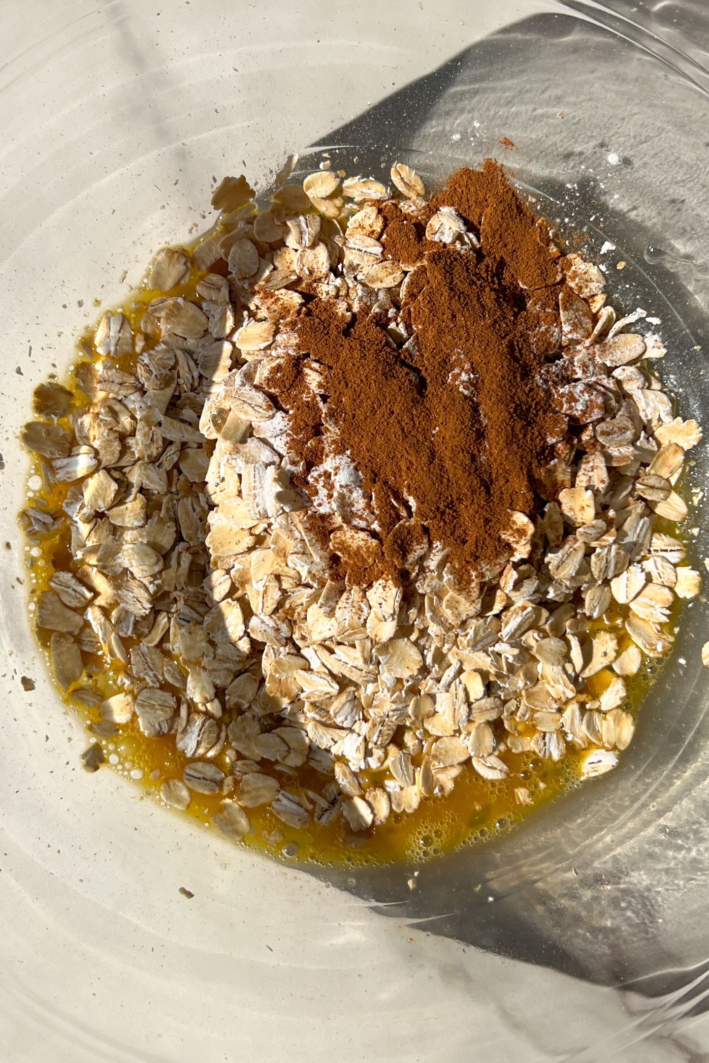 Liquid ingredients in a mixing bowl with rolled oats and cinnamon.