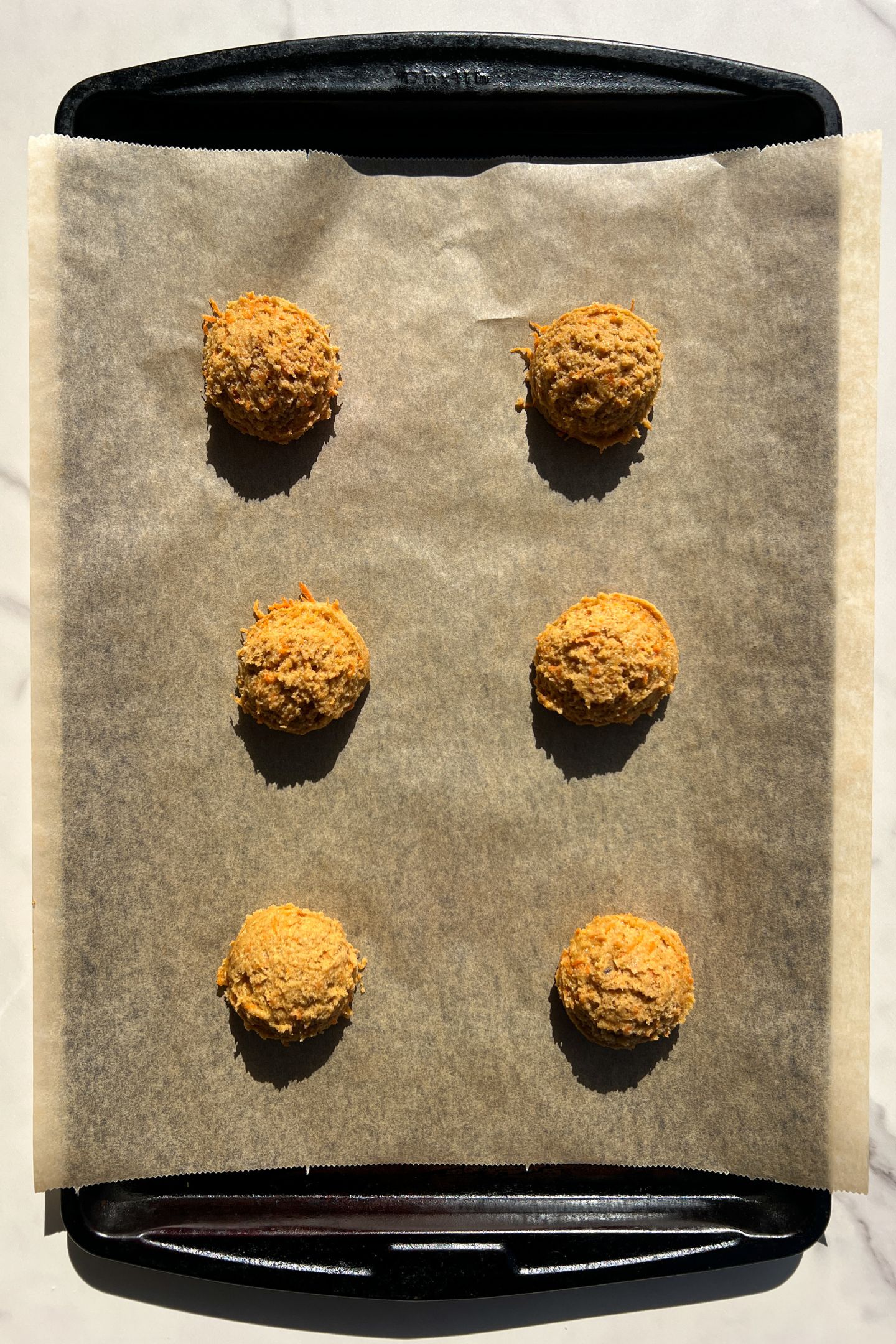 Carrot cake cookie batter scooped on parchment paper.