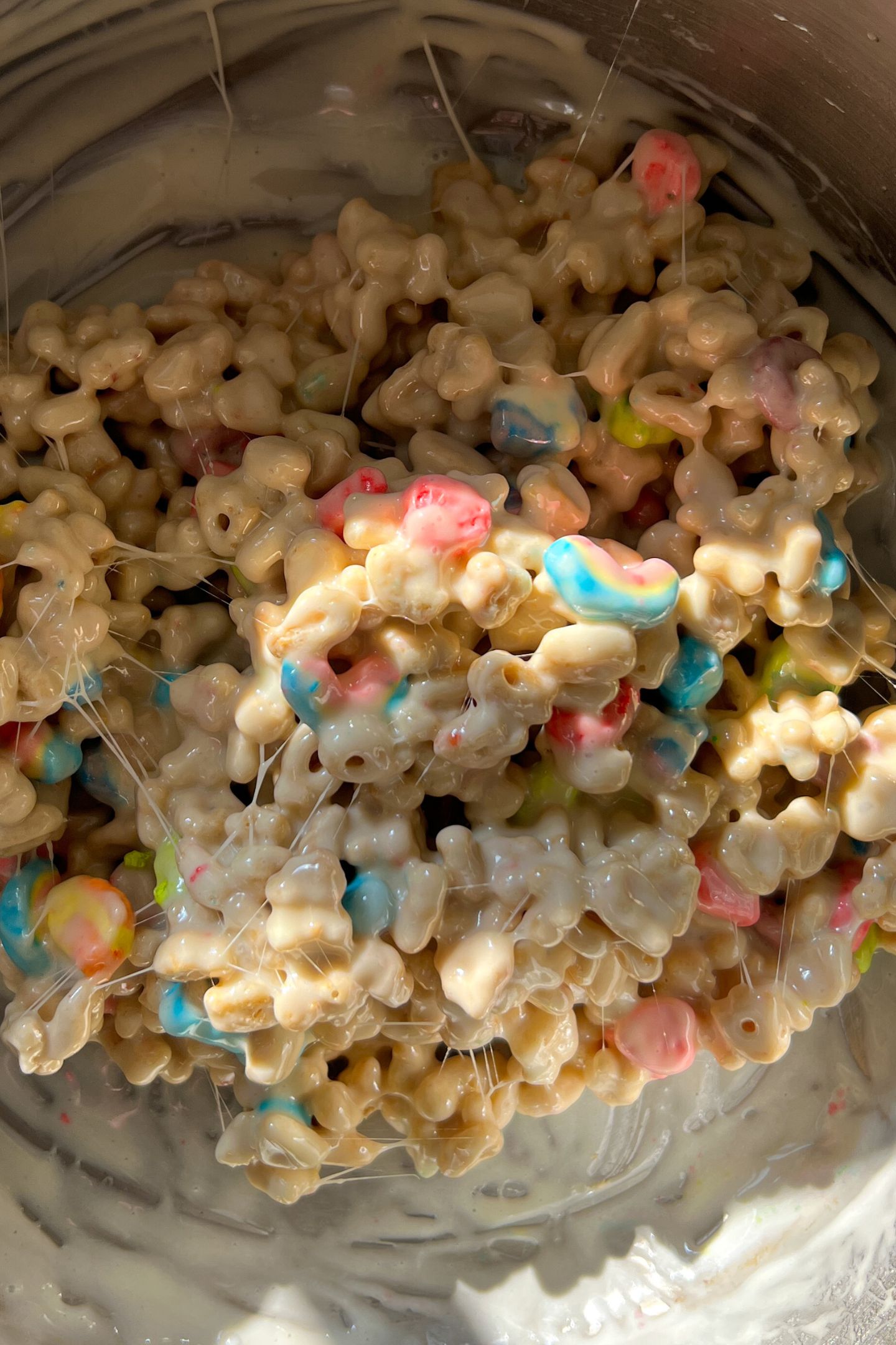 Lucky charms cereal coated in the melted marshmallow mixture in the pot.