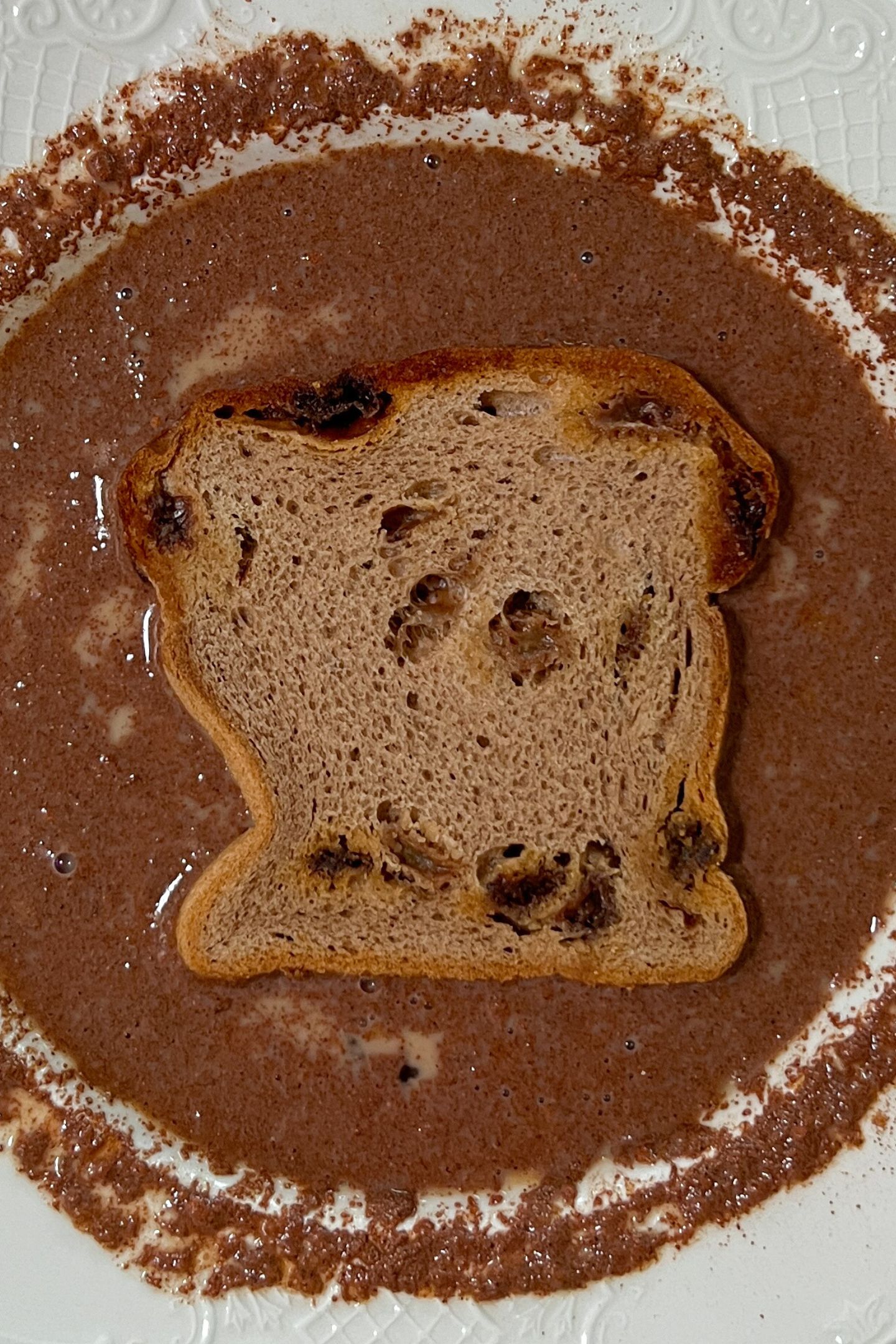 French toast egg mixture whisked in a bowl with a slice of bread.