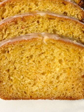 Slices of Glazed Orange Loaf stacked on each other in a row.