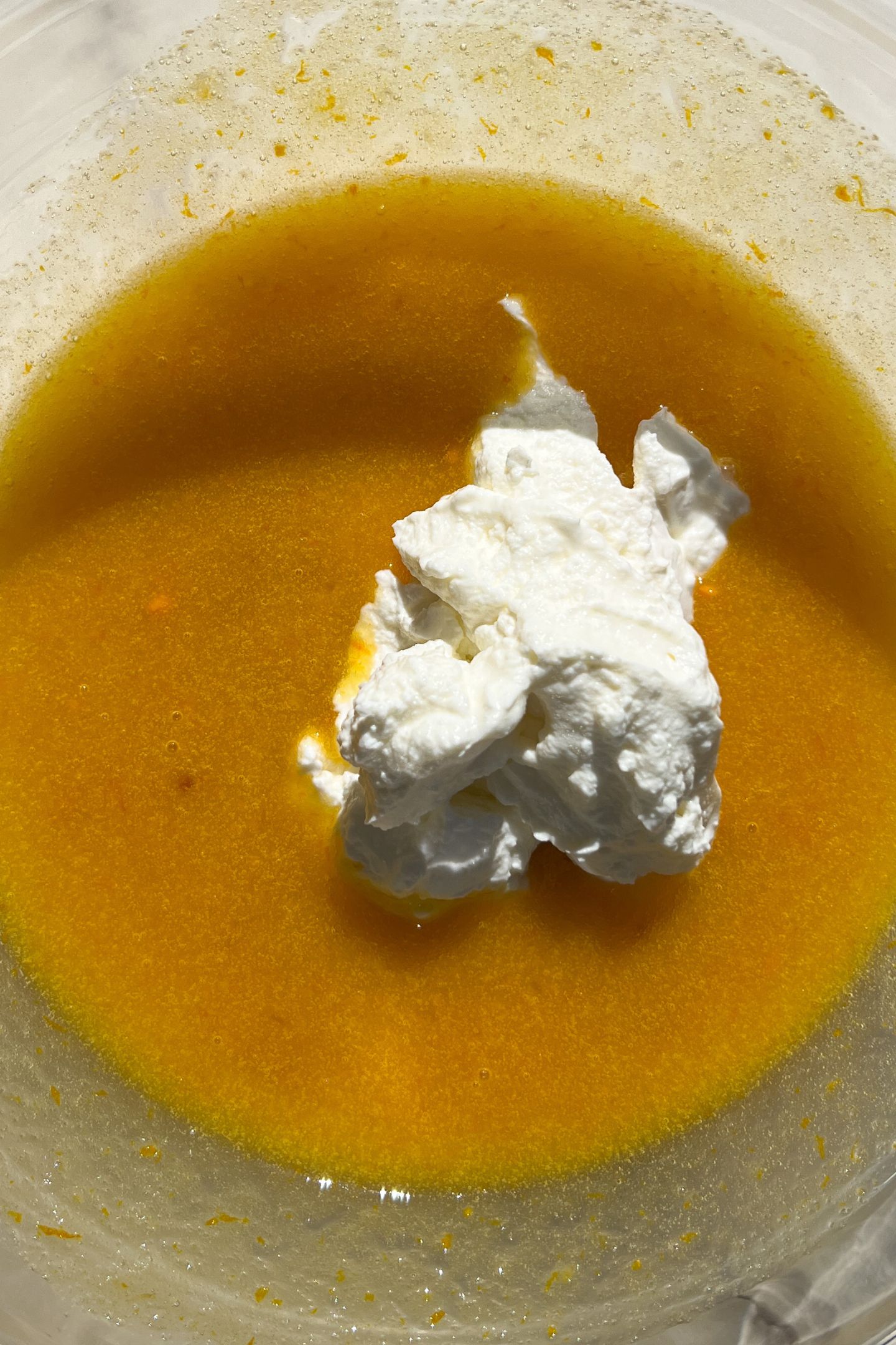 Wet ingredients in a large mixing bowl topped with greek yogurt.