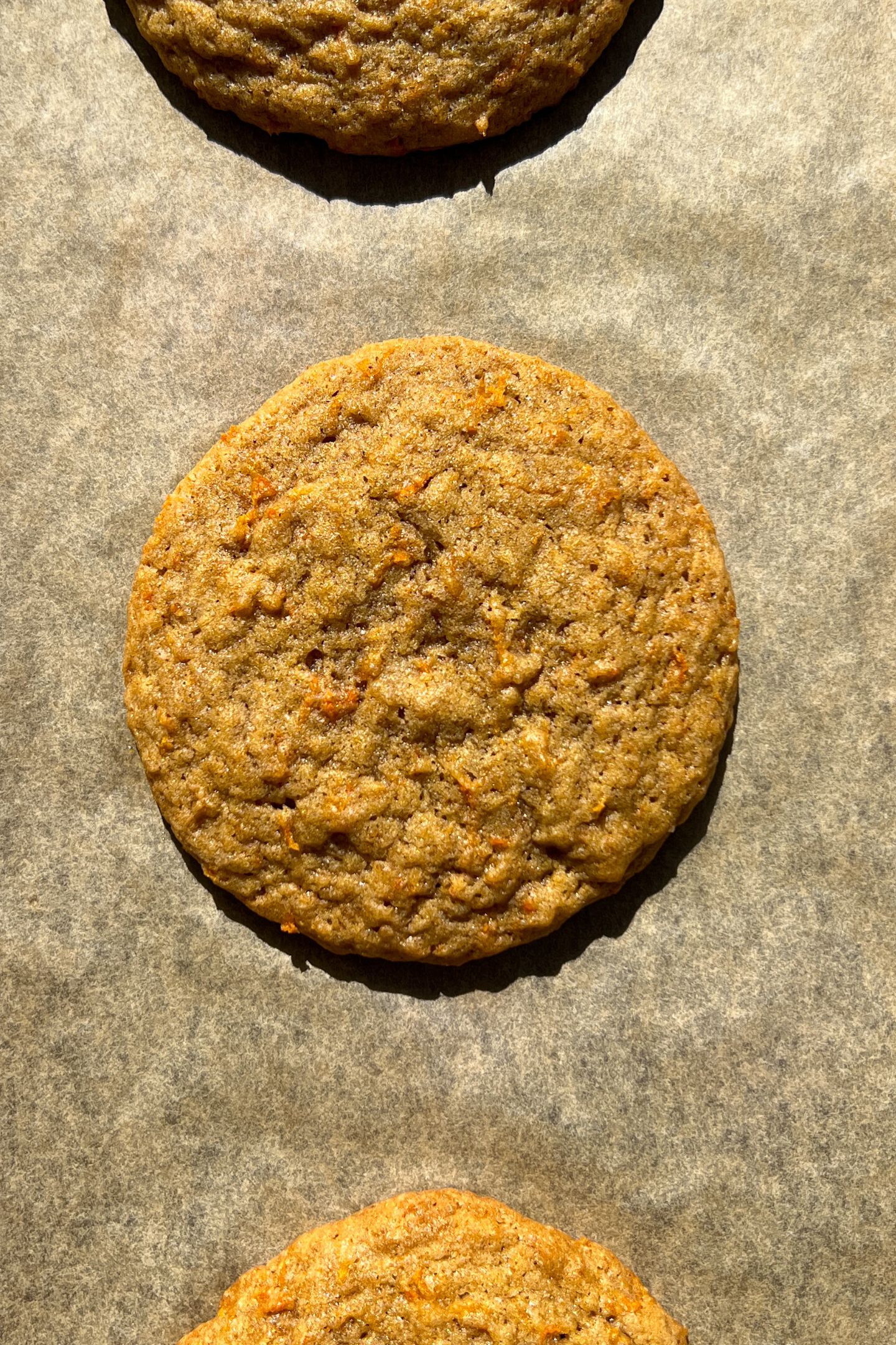A baked carrot cake cookie on parchment paper.