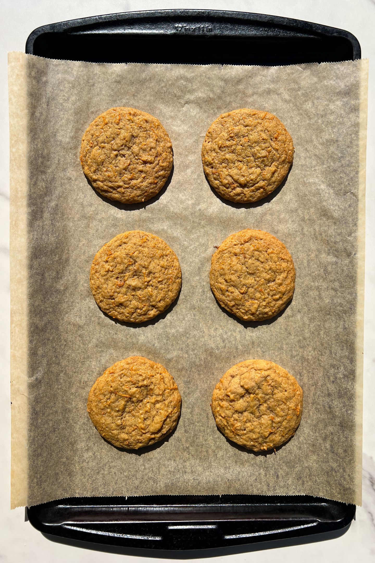 Baked carrot cake cookies cooling on parchment paper.