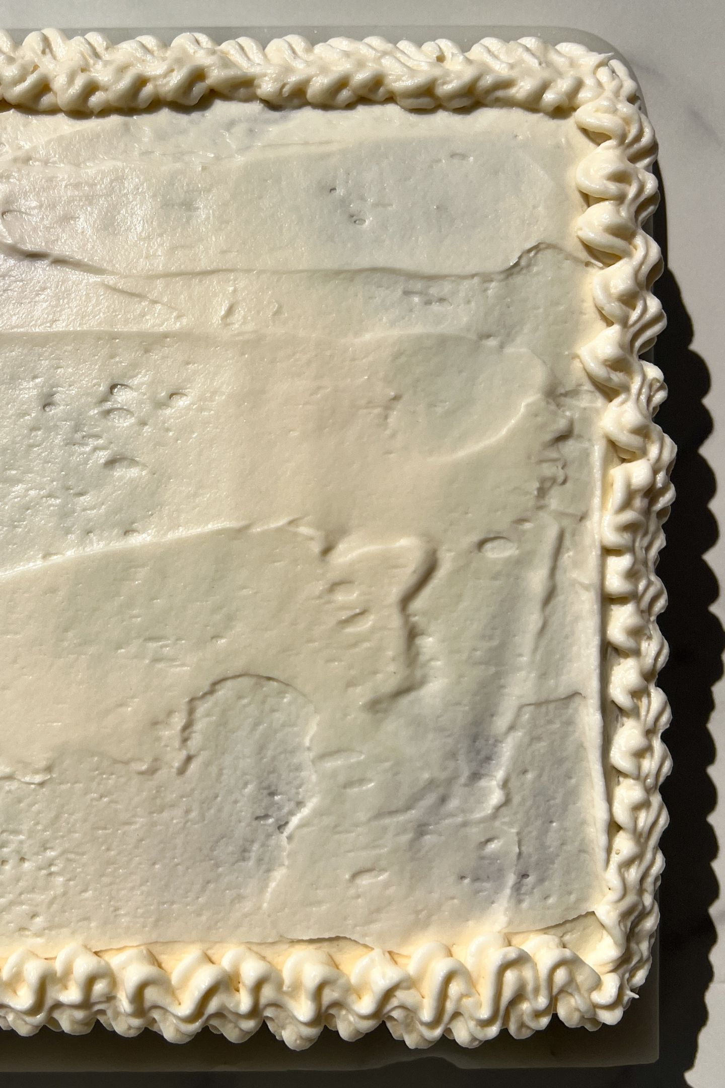 Icing the carrot cake with cream cheese frosting.