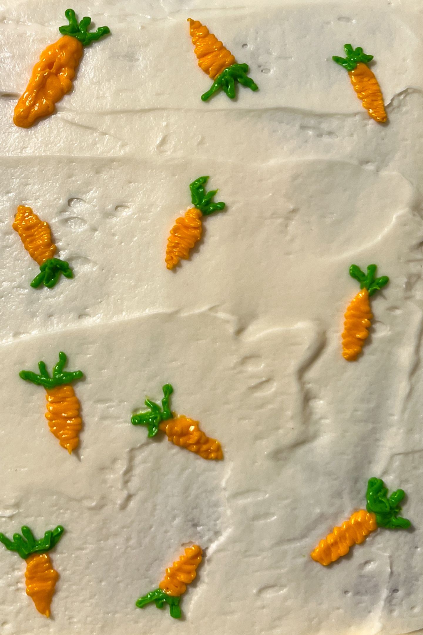 Adding frosting carrot decorations on top of the frosting.