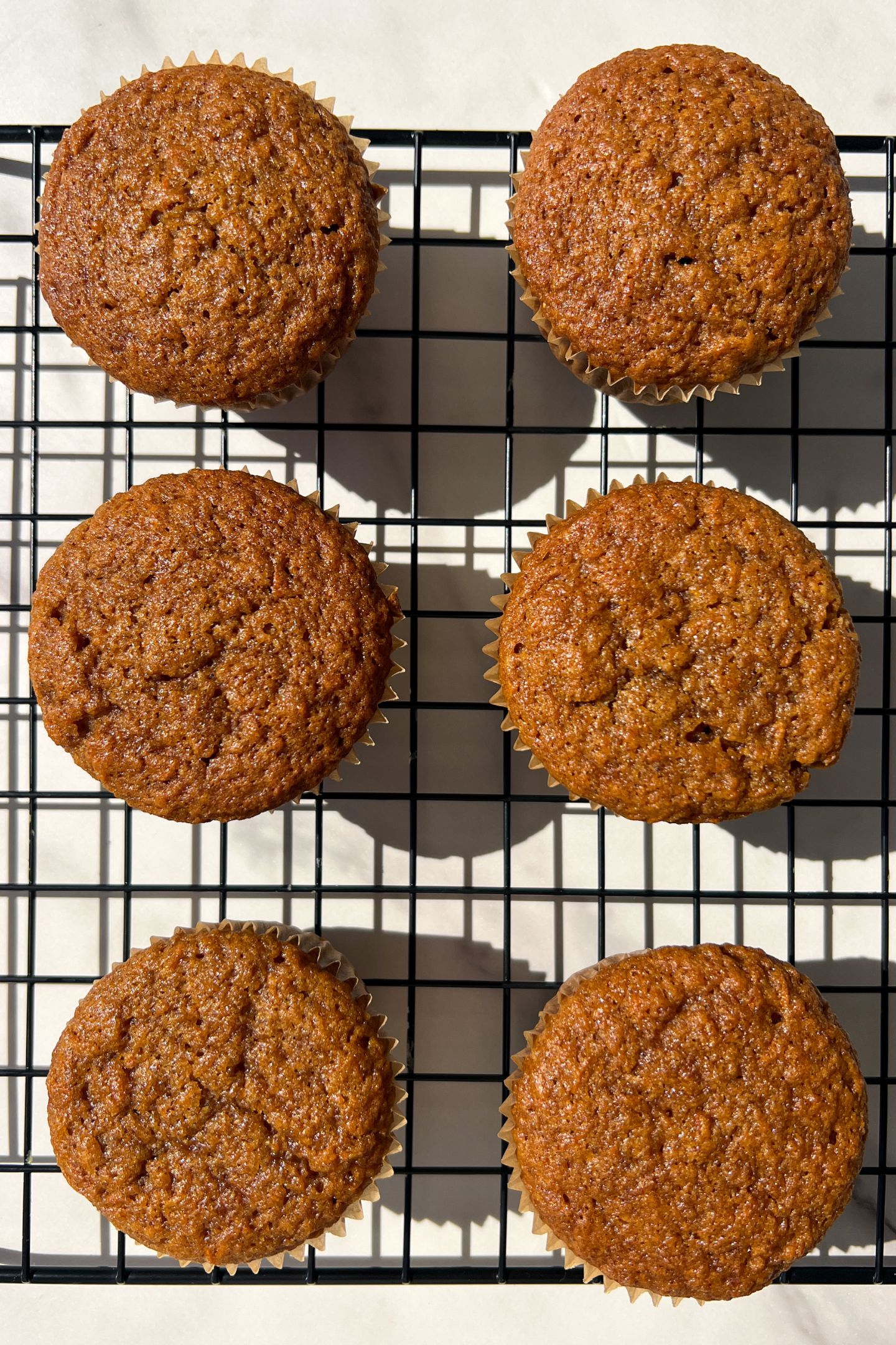 Baked and cooled Carrot Cake Cupcakes in cupcakes liners on cooling rack.