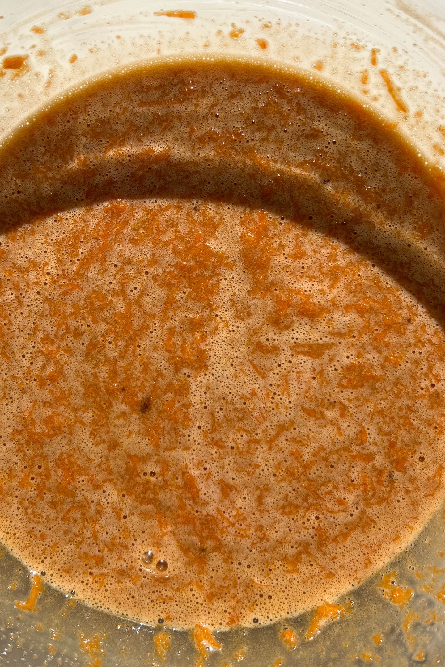 Wet ingredients and carrots in a bowl.