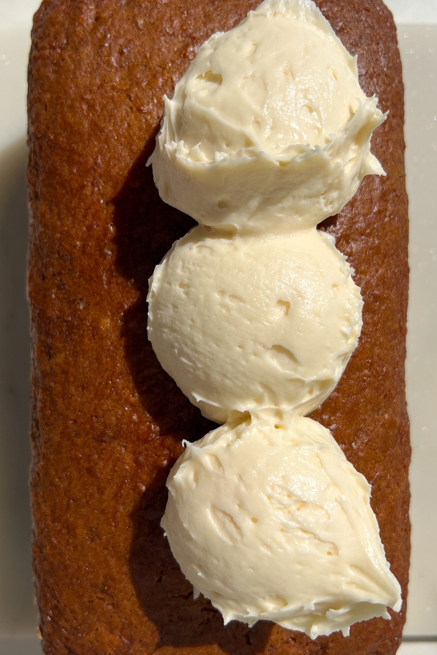 Baked Carrot Loaf Cake topped with dollops of frosting.