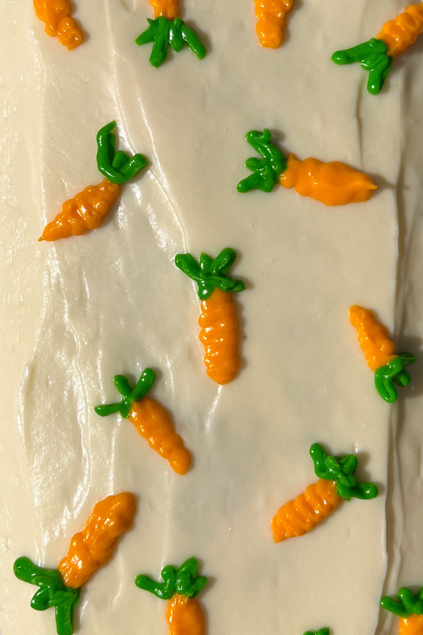 Frosted carrot cake loaf with carrot frosted decorations on top.