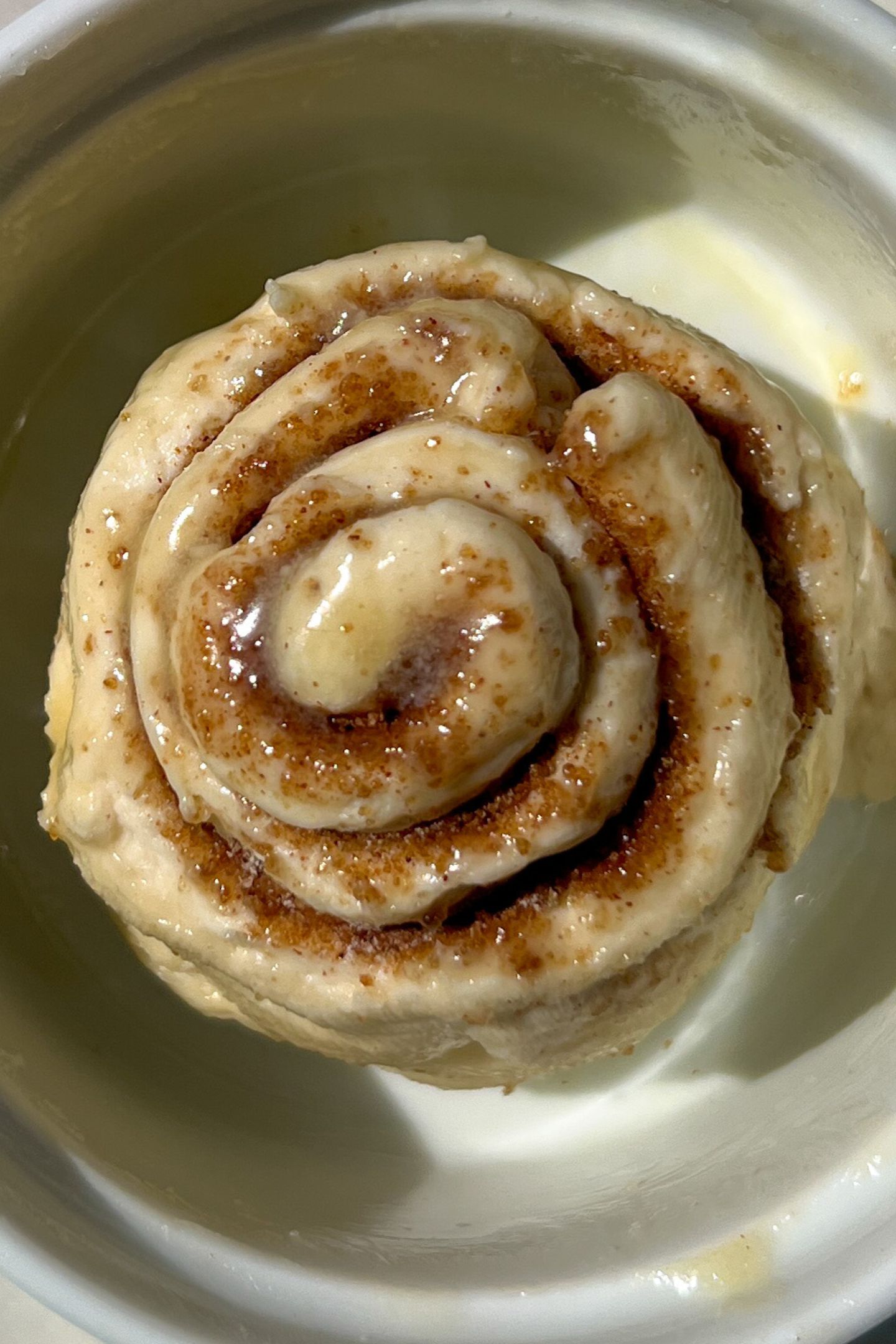Cinnamon roll in a greased dish brushed with melted butter.