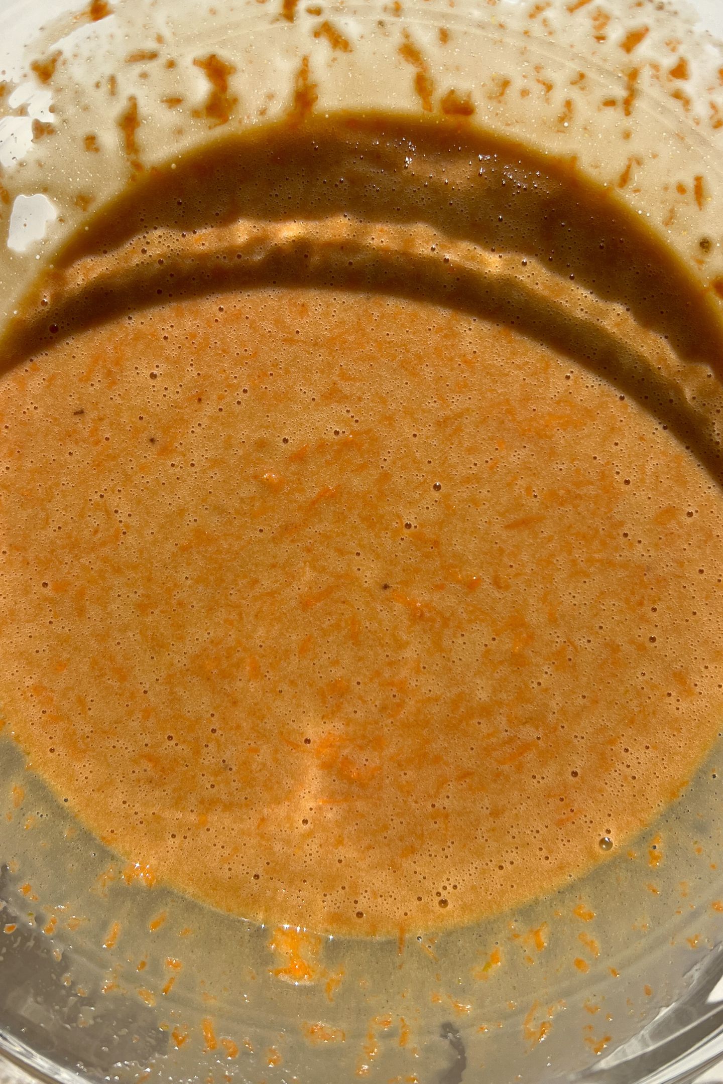 Wet ingredients in mixing bowl with grated carrots.