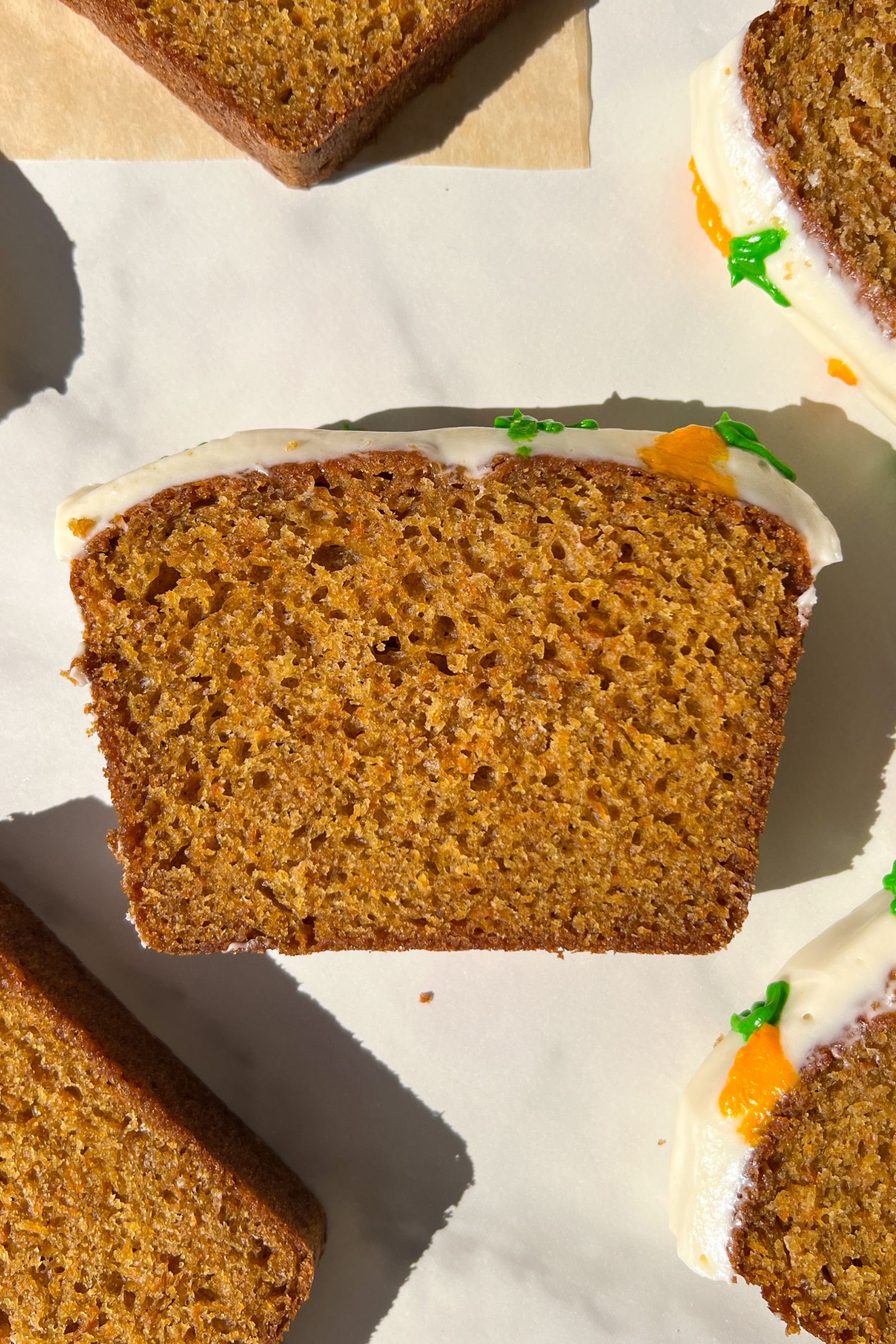 Slices of Frosted Carrot Loaf Cake with carrot frosting decorations.