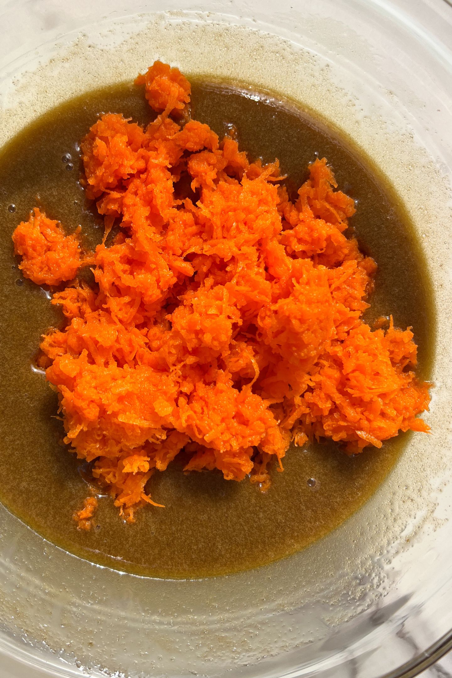Wet ingredients and grated carrots in mixing bowl.