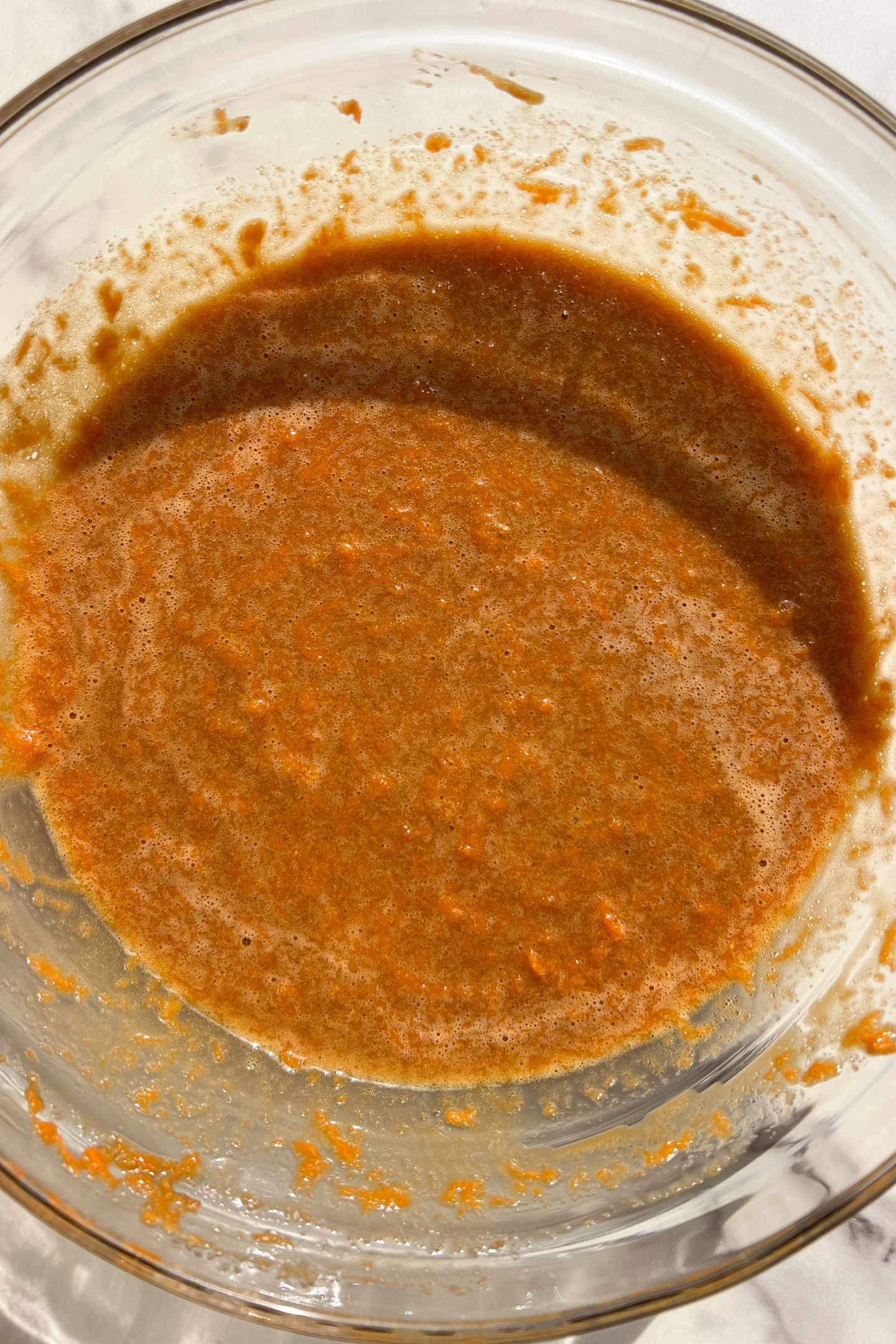 Wet ingredients and grated carrots combined in mixing bowl.