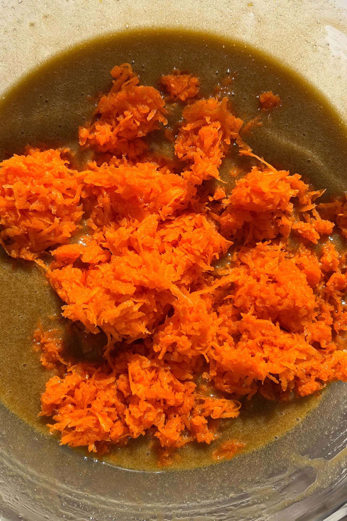 Wet ingredients in a mixing bowl whisked together with carrots.