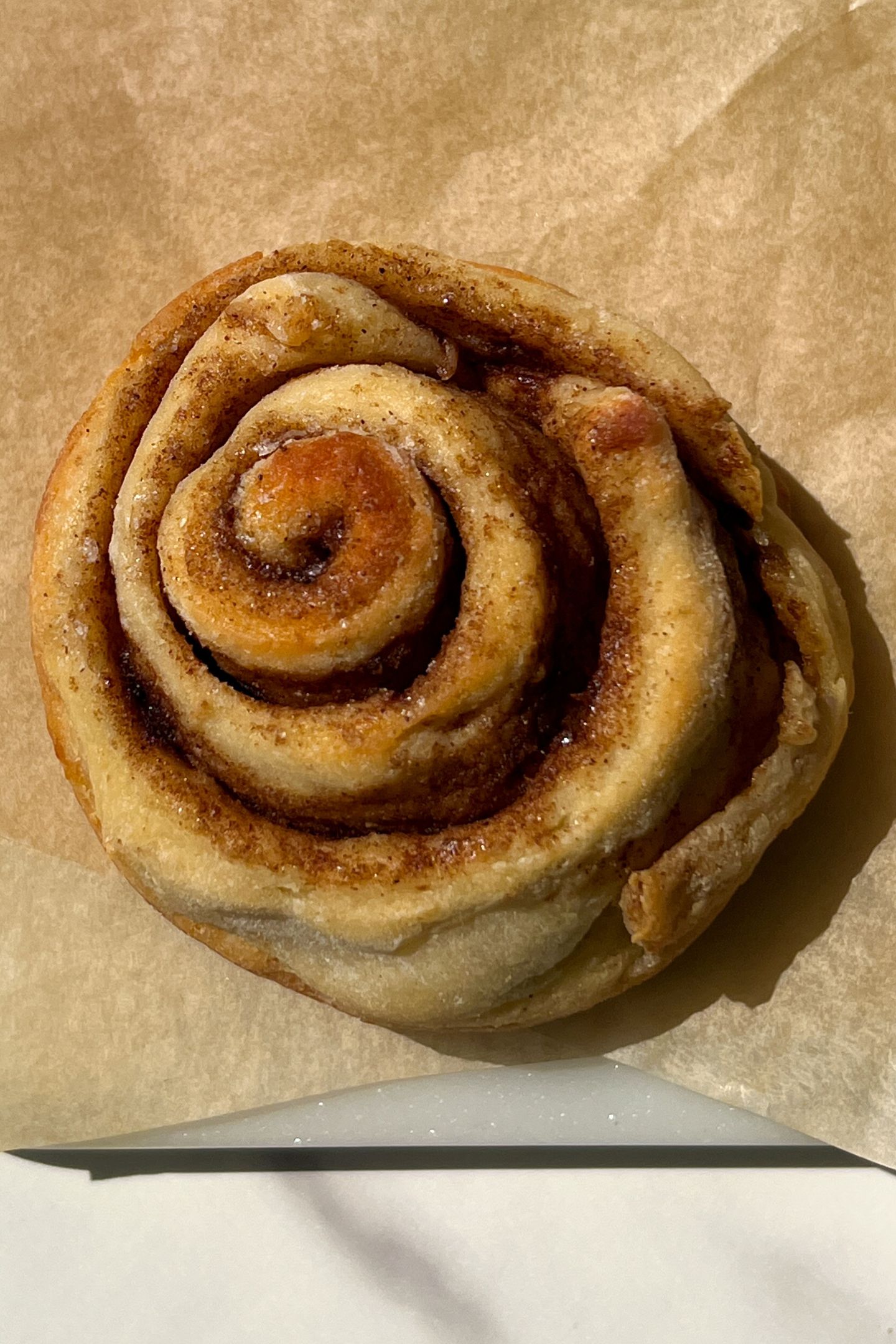 Baked cinnamon roll on parchment paper.