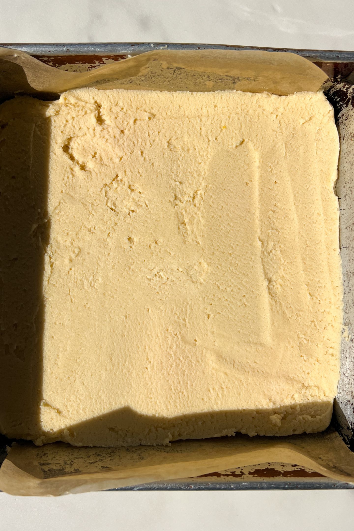 Dough spread into a greased 8x8 square pan lined with parchment.