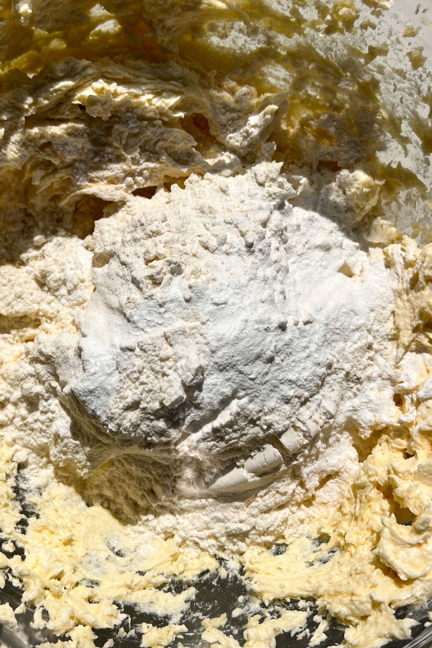 Wet ingredients blended together in a mixing bowl topped with dry ingredients. 