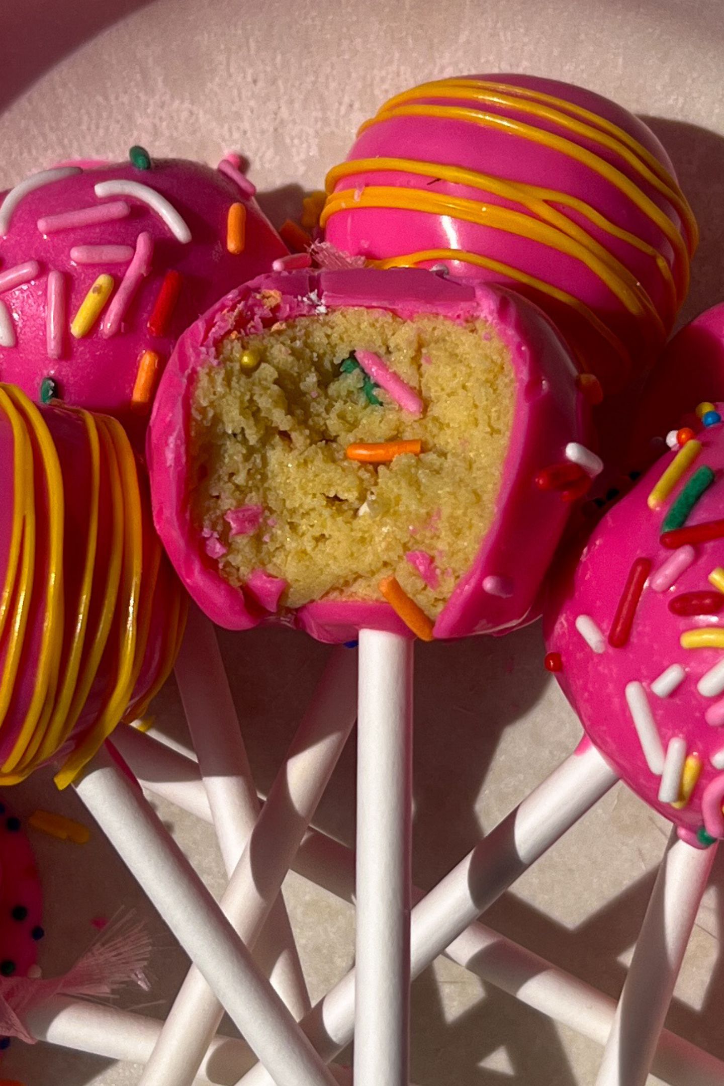Barbie cake pops on a plate with one having a bite taken out of it.