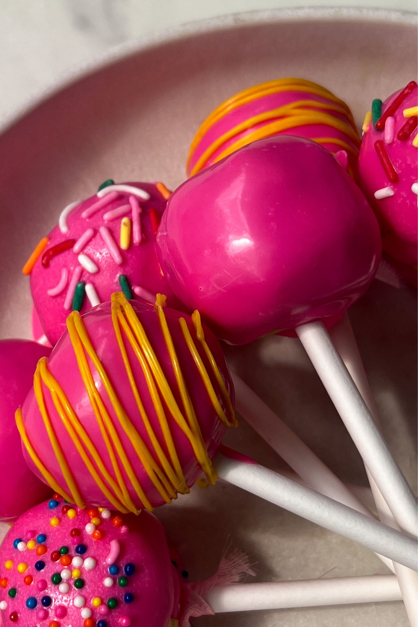 Cake pops with decorations and sprinkles in a serving bowl.