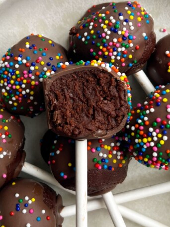 Fudgy Brownie Cake Pops on a platter with a bite taken out of one.
