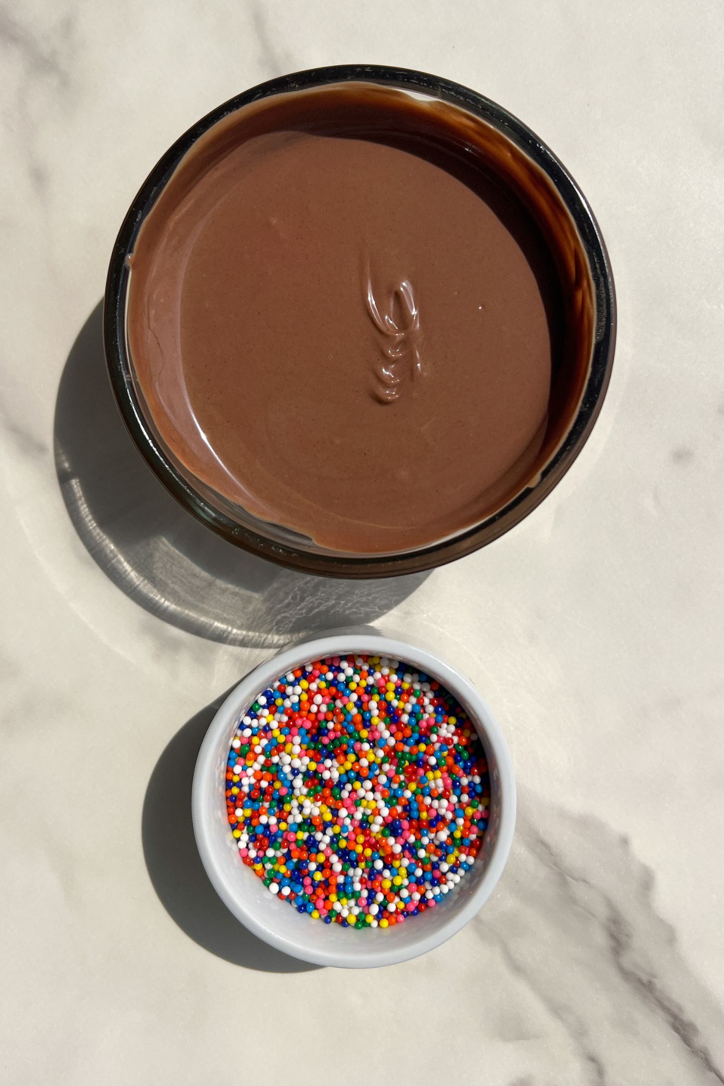 Melted chocolate wafers and sprinkles in bowls.
