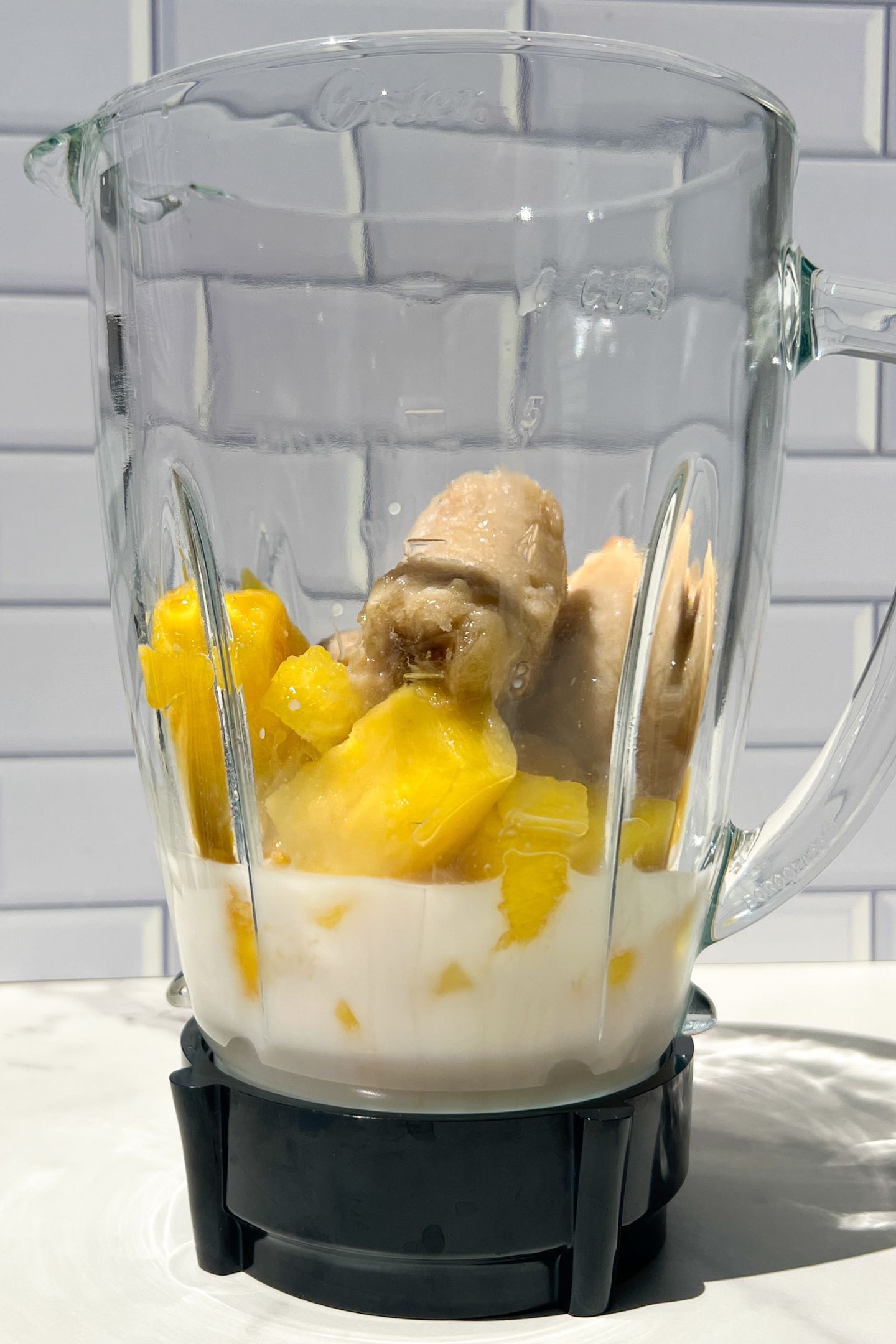Liquid, frozen pineapple and banana in blender.