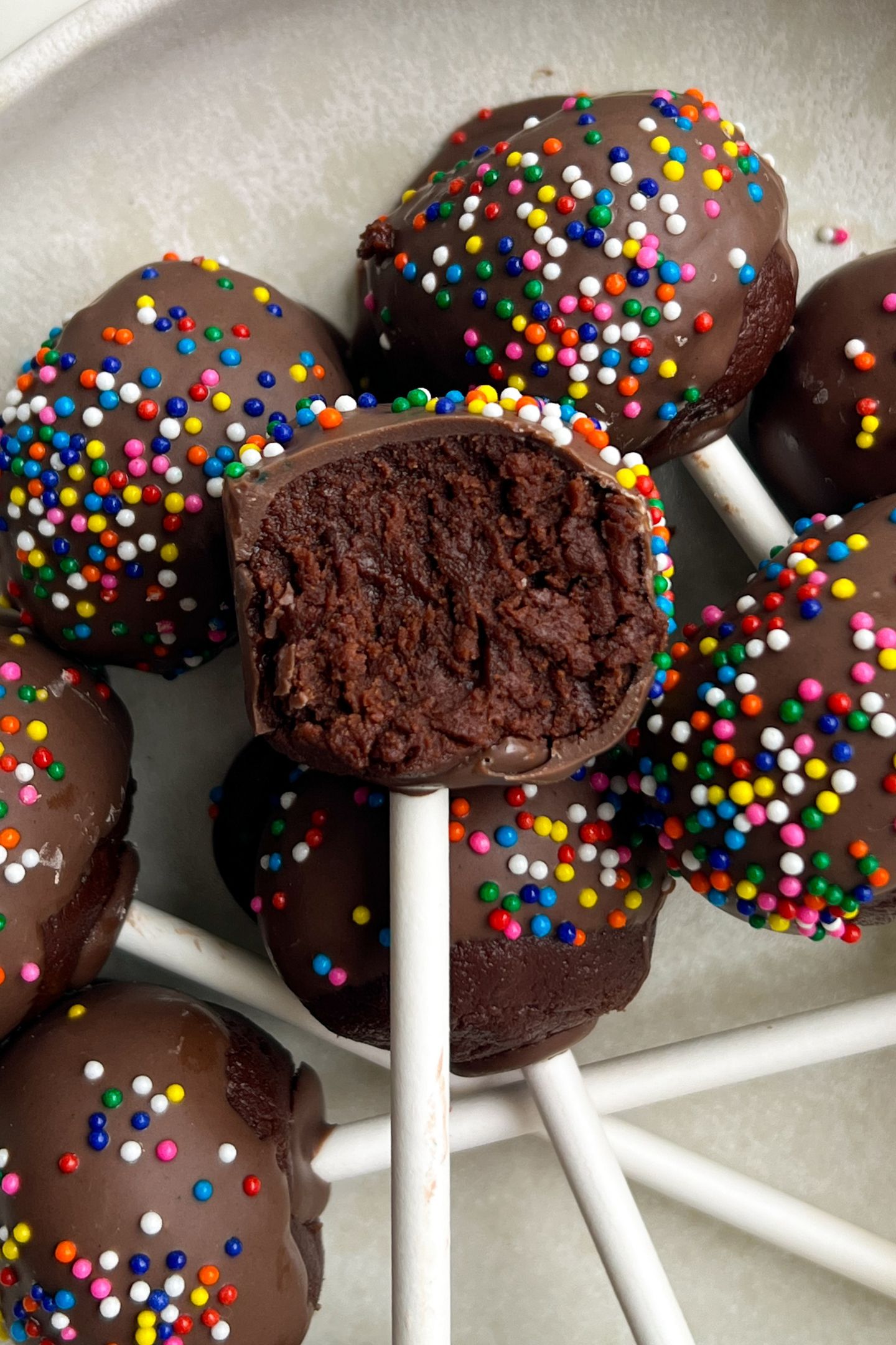 Brownie cake pop on a platter with a bite taken out of it.
