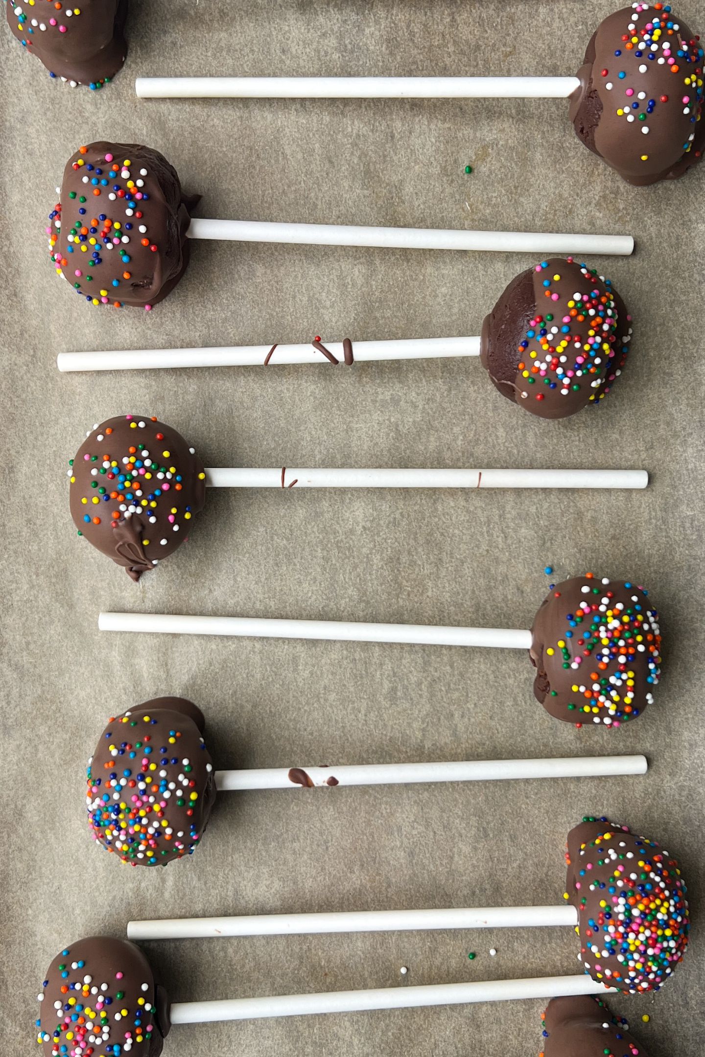 Brownie cake pops on a baking sheet lined with parchment paper.