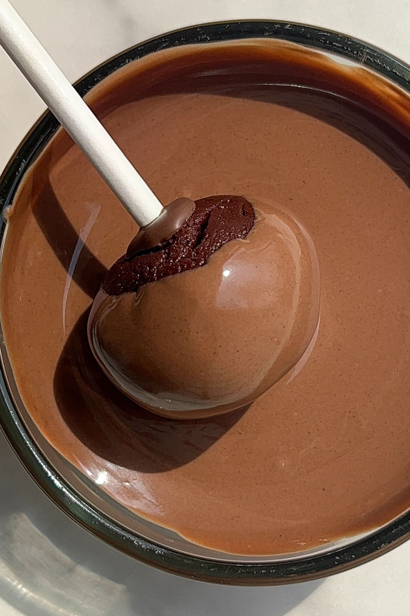 Dipping a brownie pop in melted chocolate.