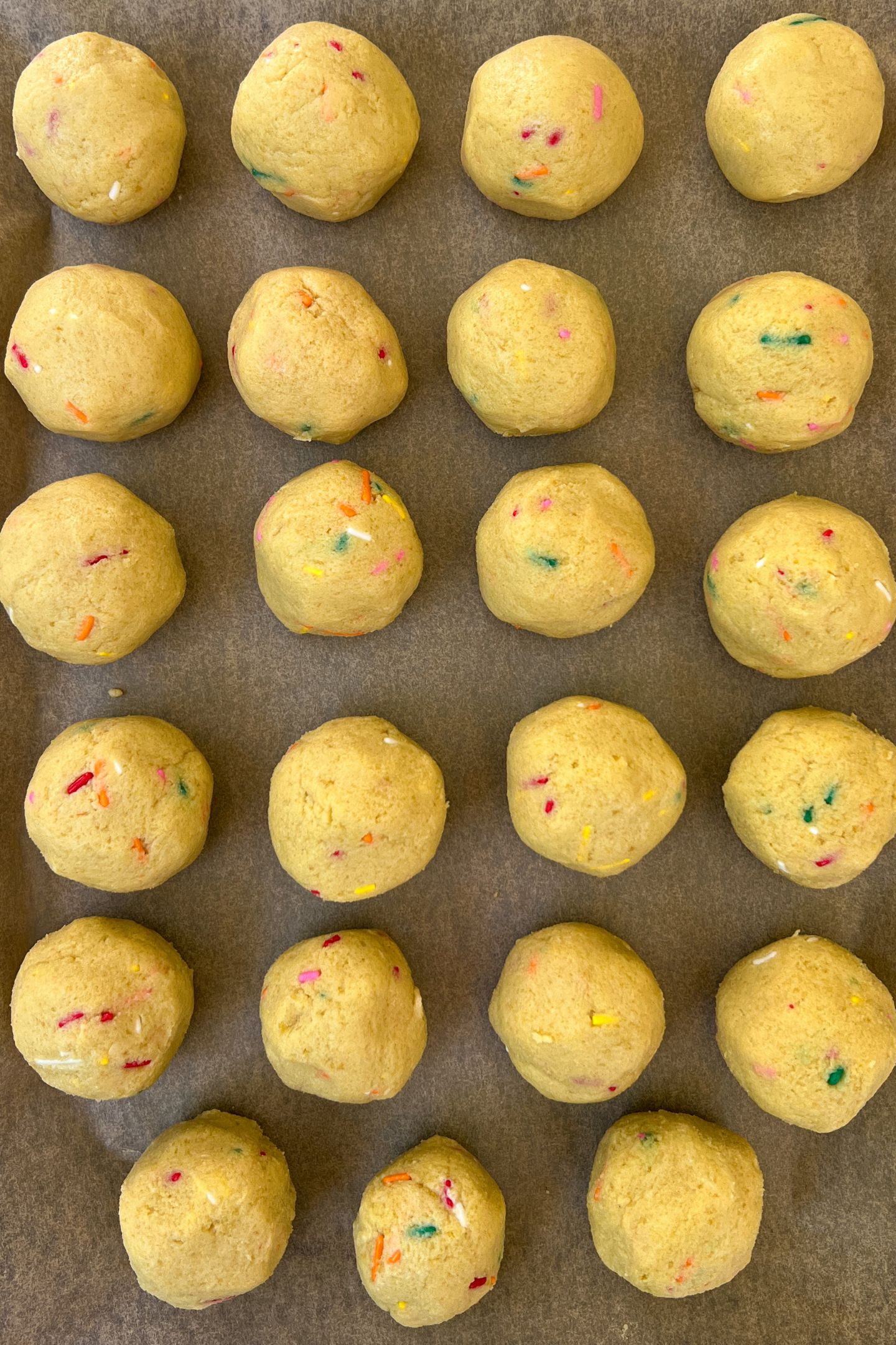 Cake pop balls on a tray lined with parchment paper.