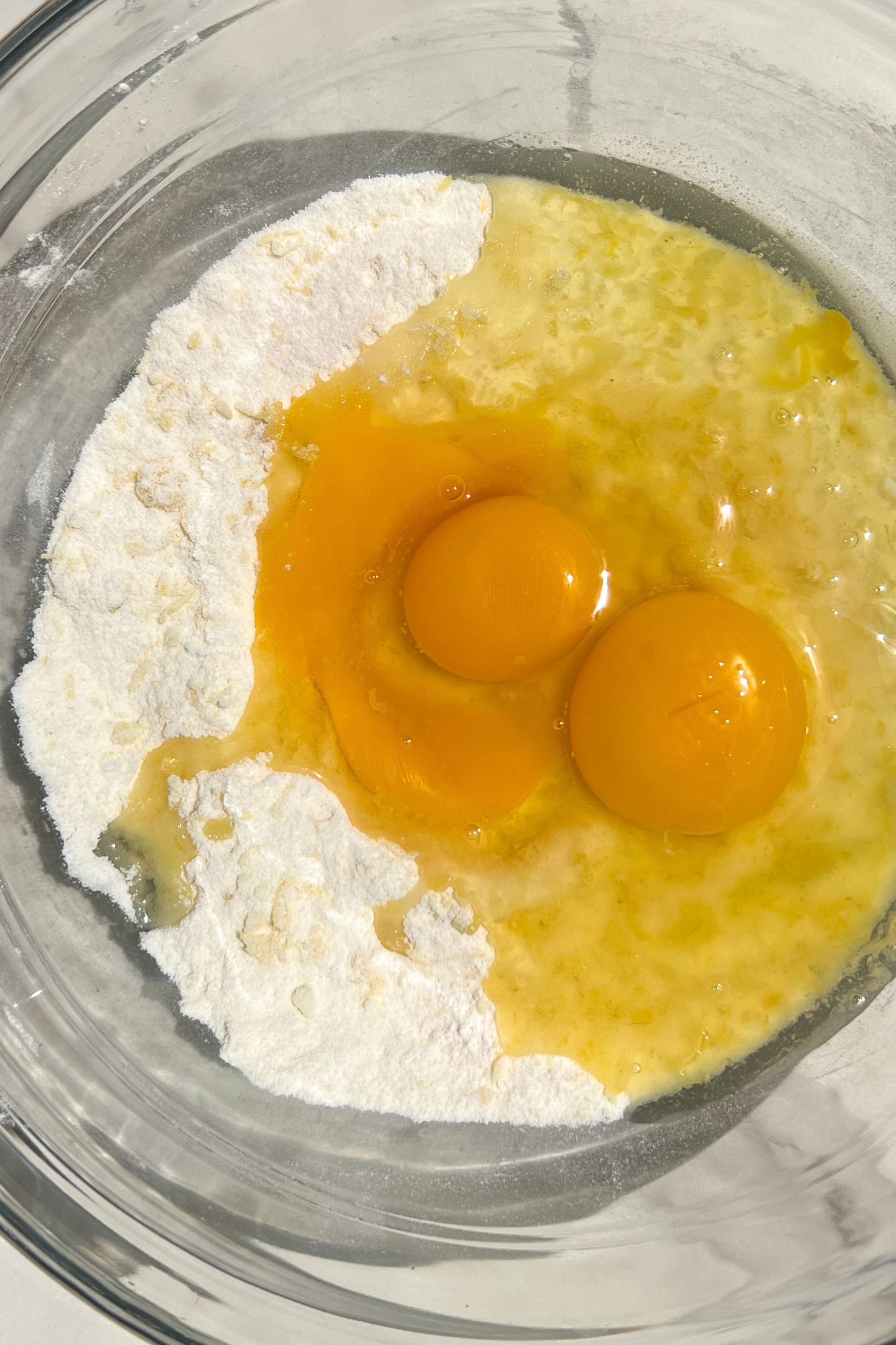 Granulated sugar, lemon zest and eggs in a bowl.