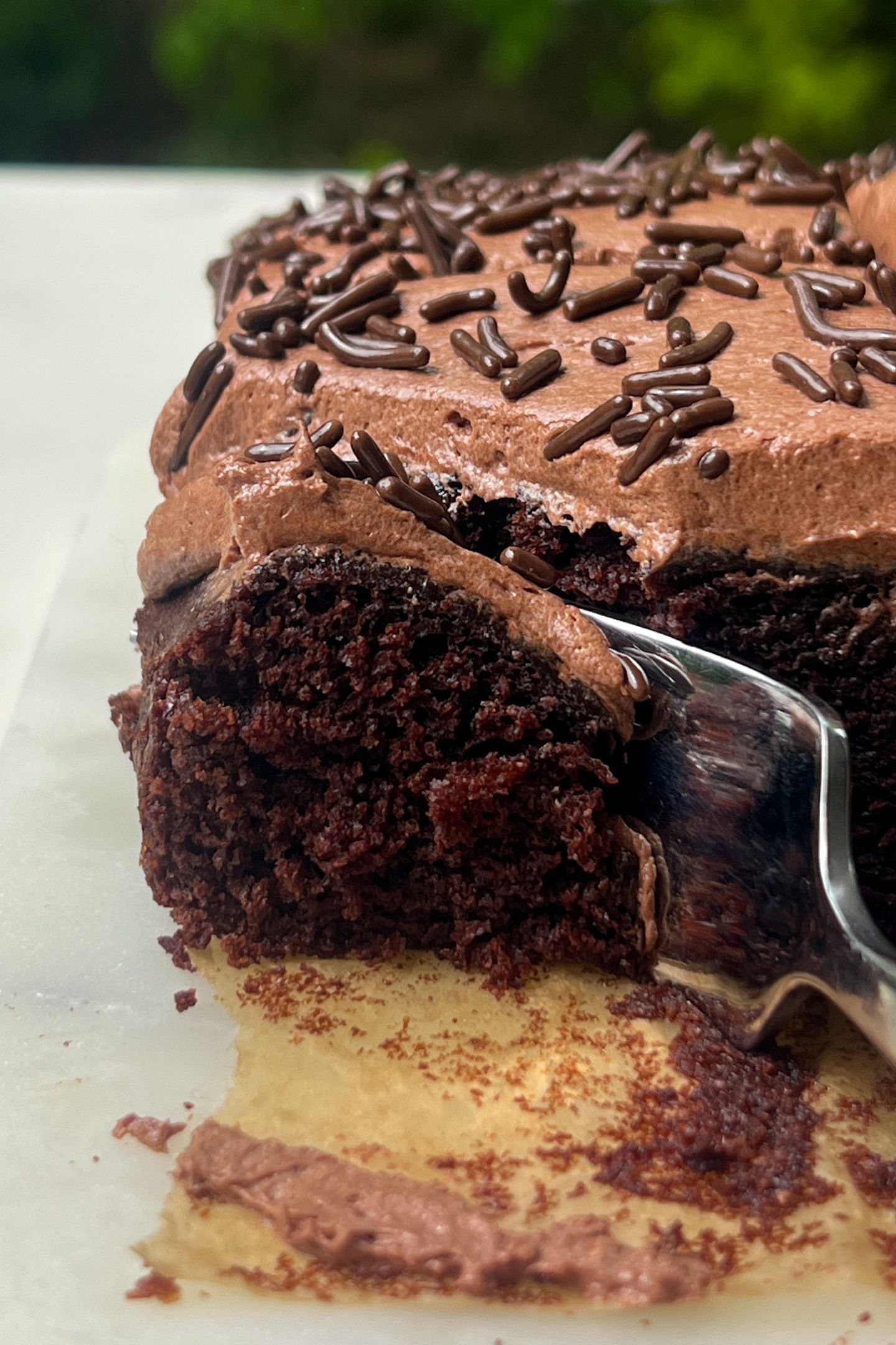 Eating a piece of chocolate cake with chocolate cream cheese frosting using a fork.