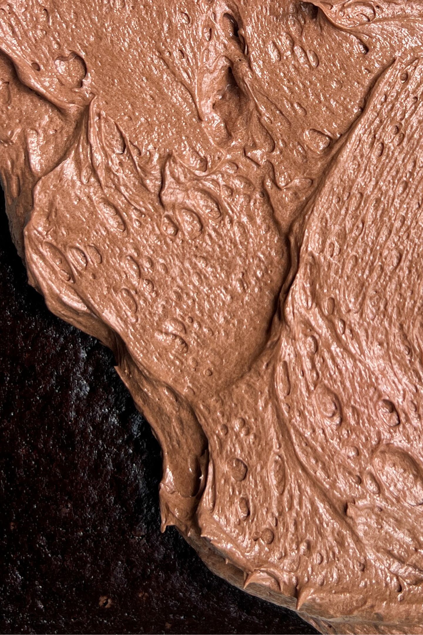 Adding chocolate frosting to cake.