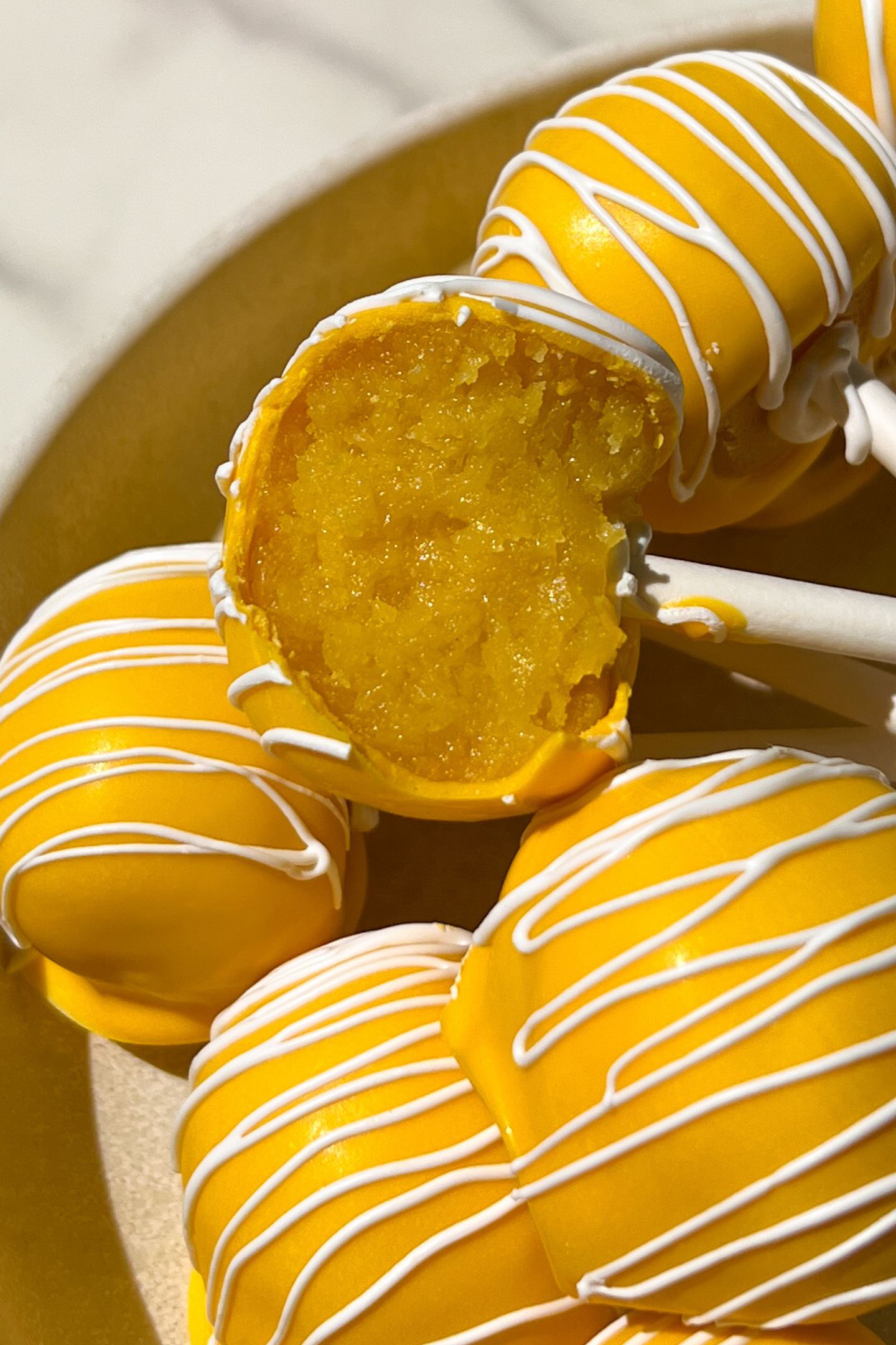 Lemon cake pop with a bite taken out of it.