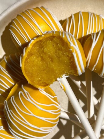 A lemon cake pop with a bite taken out of it.