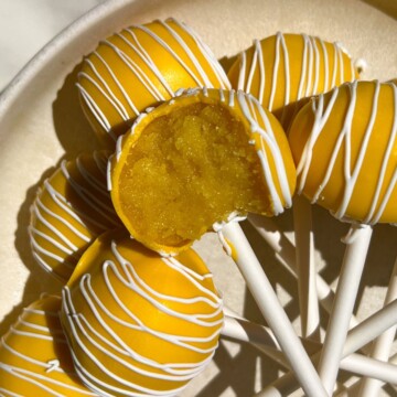 A lemon cake pop with a bite taken out of it.