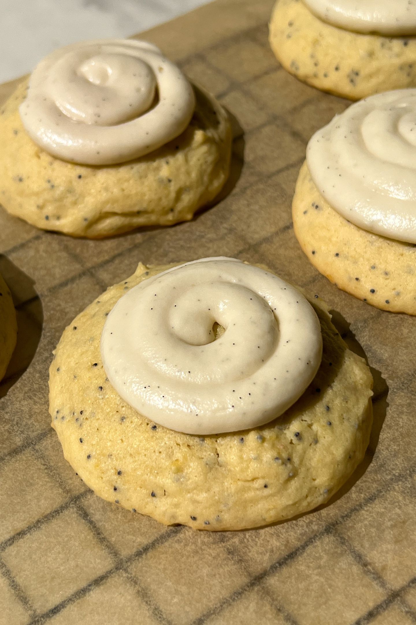 Lemon poppy cookie topped with a swirl of vanilla frosting.