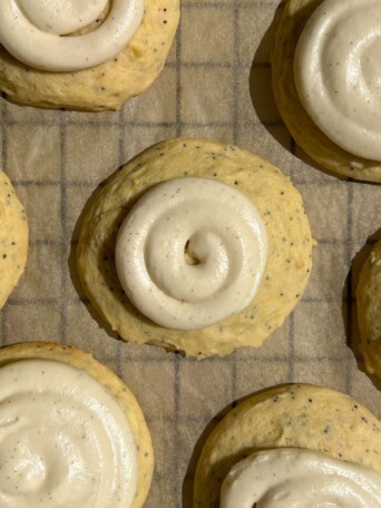 Lemon poppy seed cookies with frosting swirled on top.