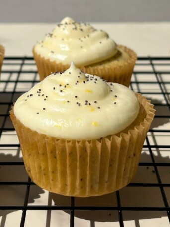 Frosted Lemon Poppy Seed Cupcakes on a cooling rack.