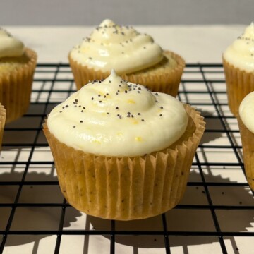 Frosted Lemon Poppy Seed Cupcakes on a cooling rack.