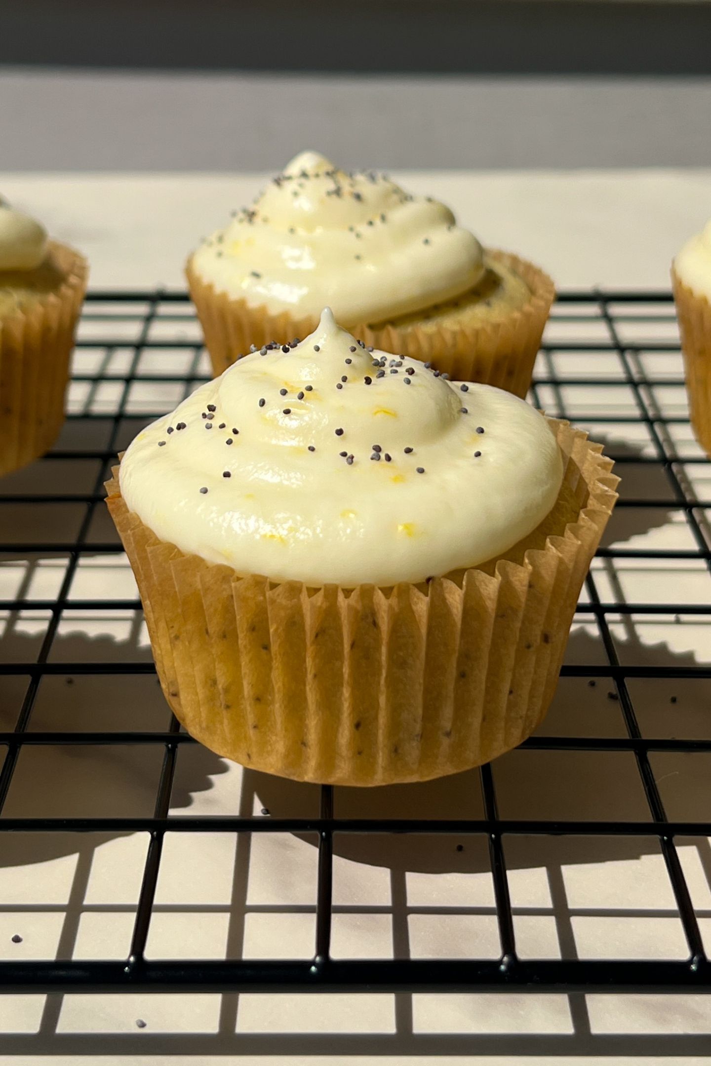 Decorated lemon poppy seed cupcakes on a cooling rack.