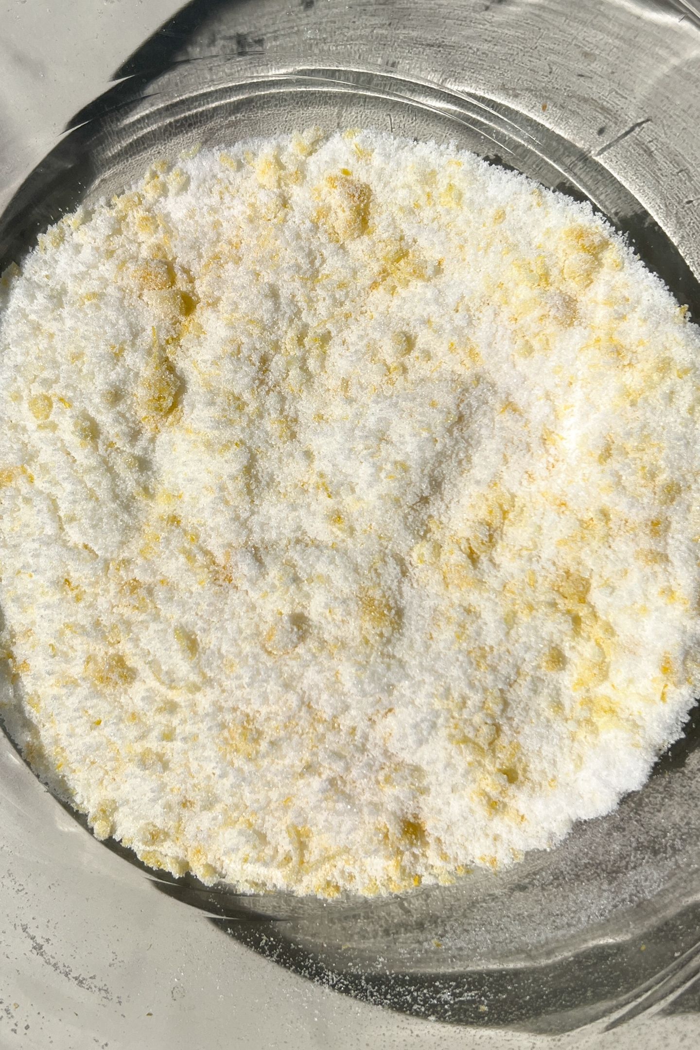 Lemon zest and granulated sugar combined together in a mixing bowl.