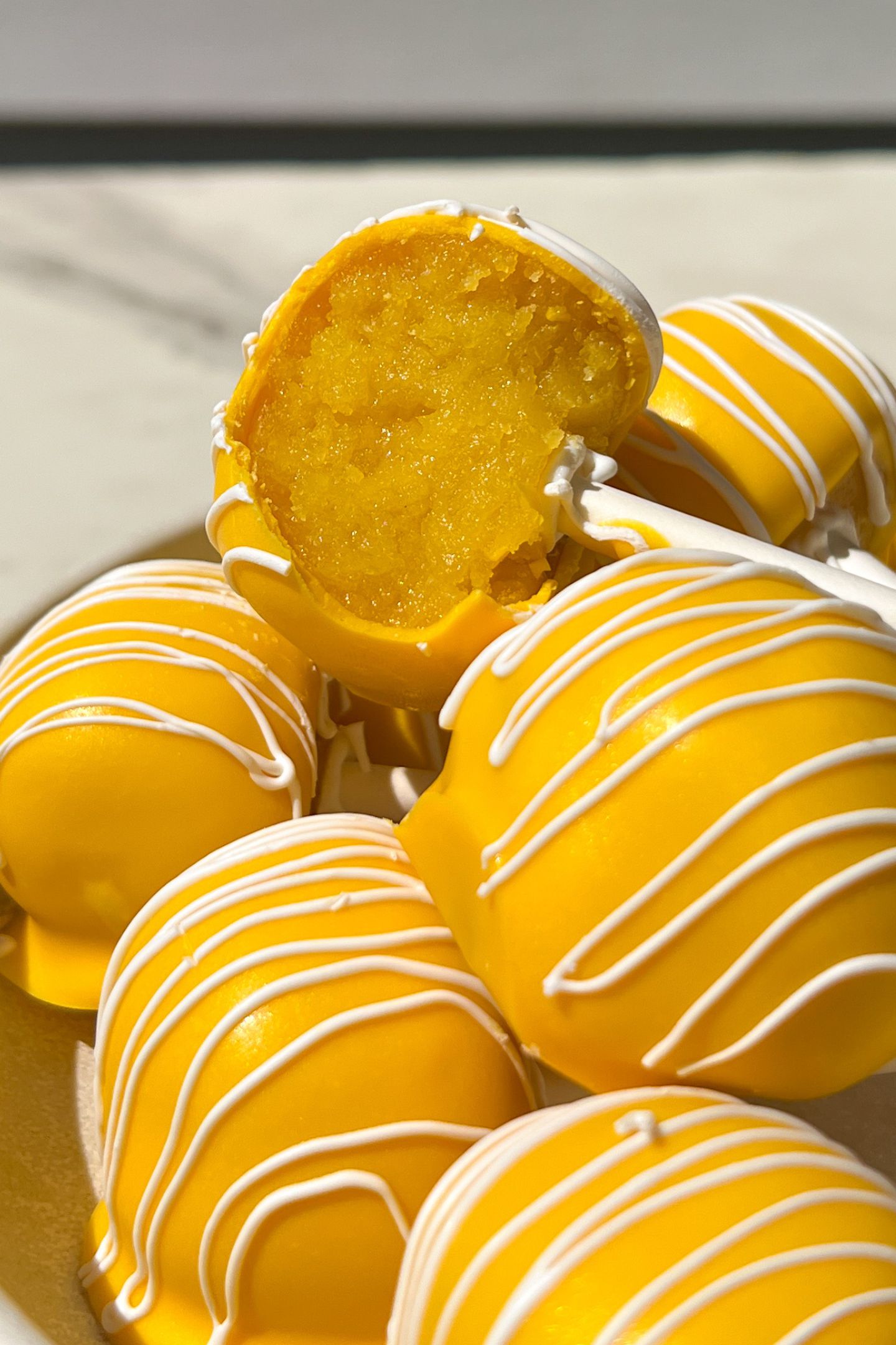 Cake pops on a platter with one having a bite taken out of it.