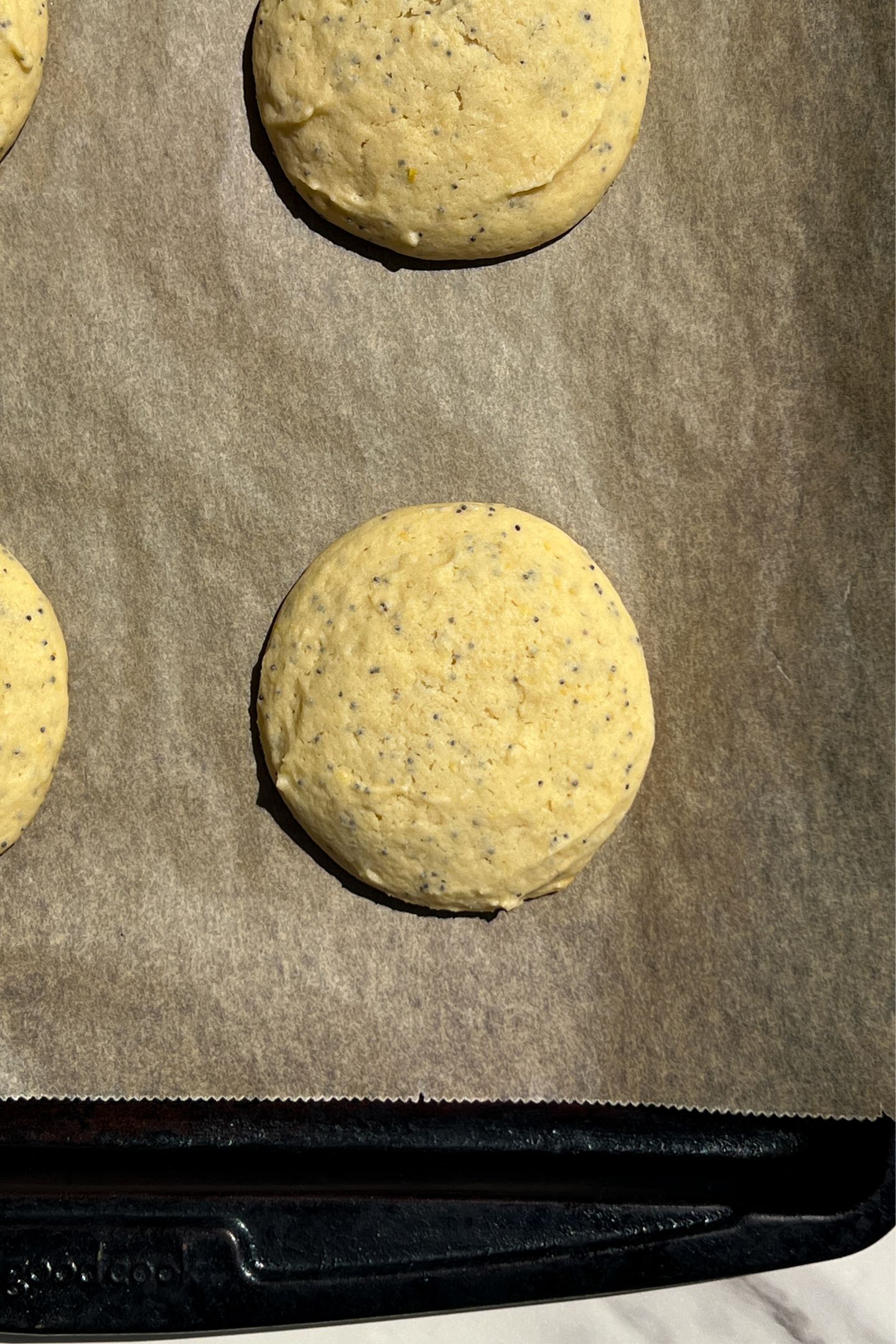 Baked lemon poppy seed cookies on parchment paper.