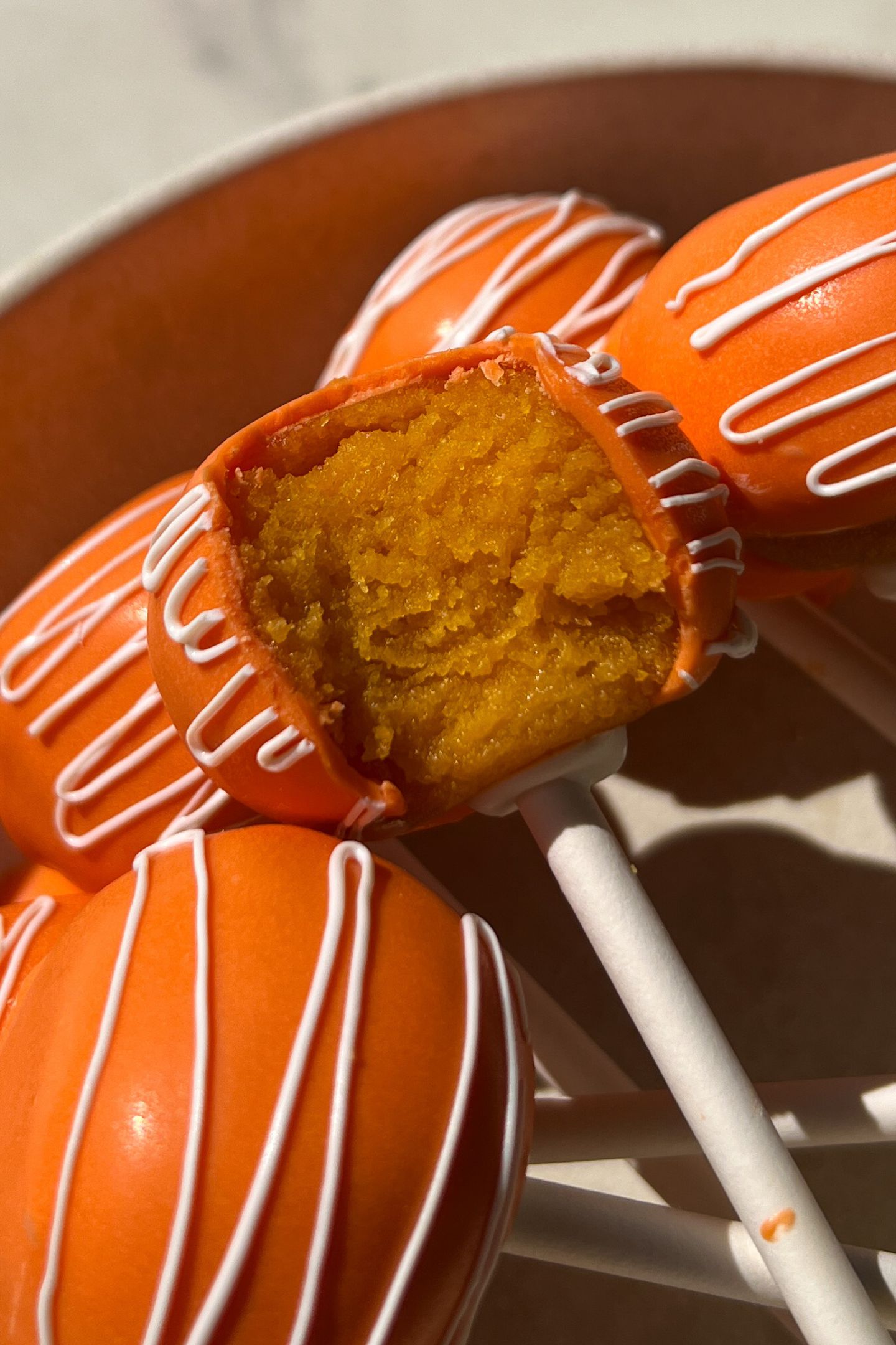 Orange Cake Pops with one having a bite taken out of it.