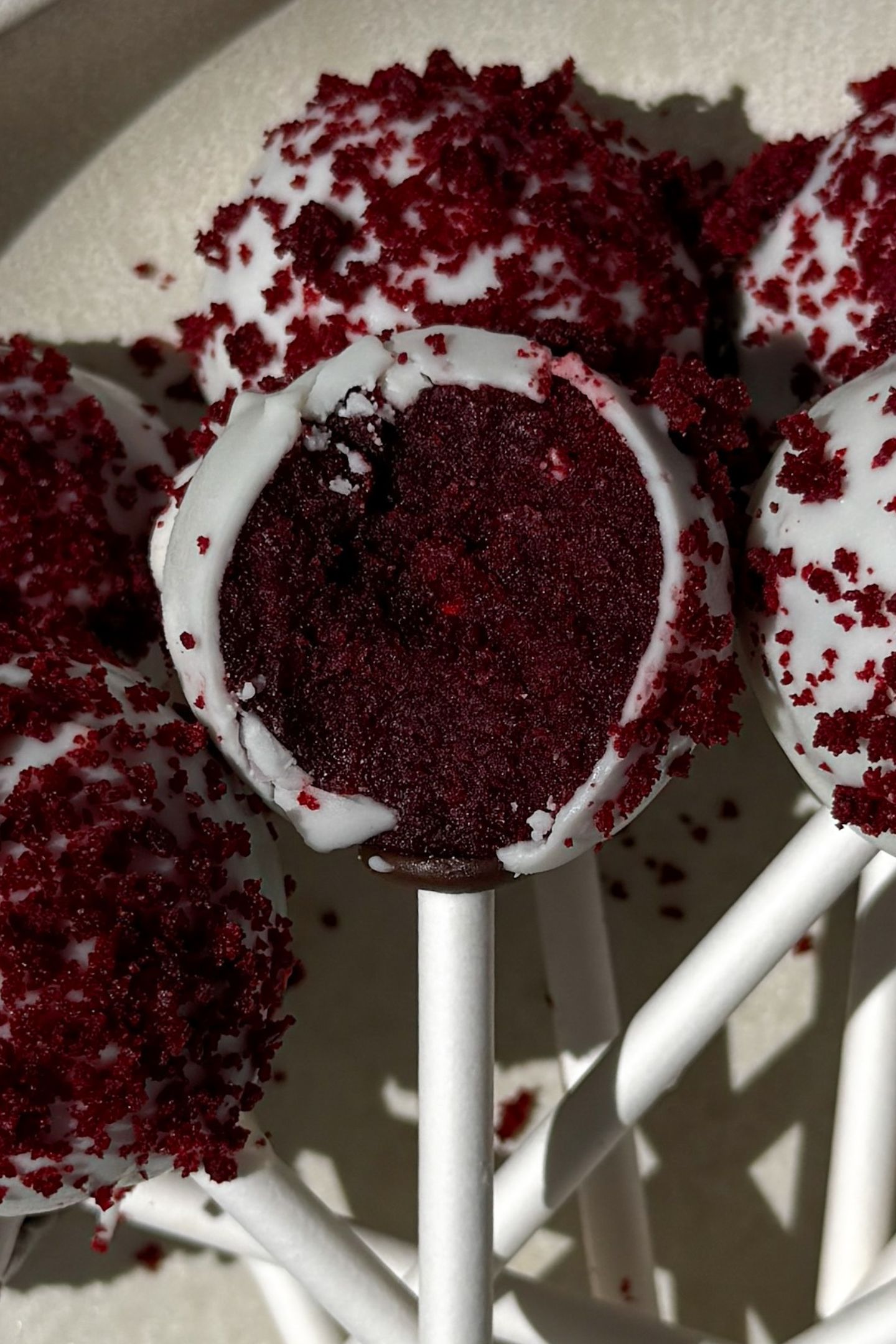Cake pops on a platter with one having a bite taken out of it.
