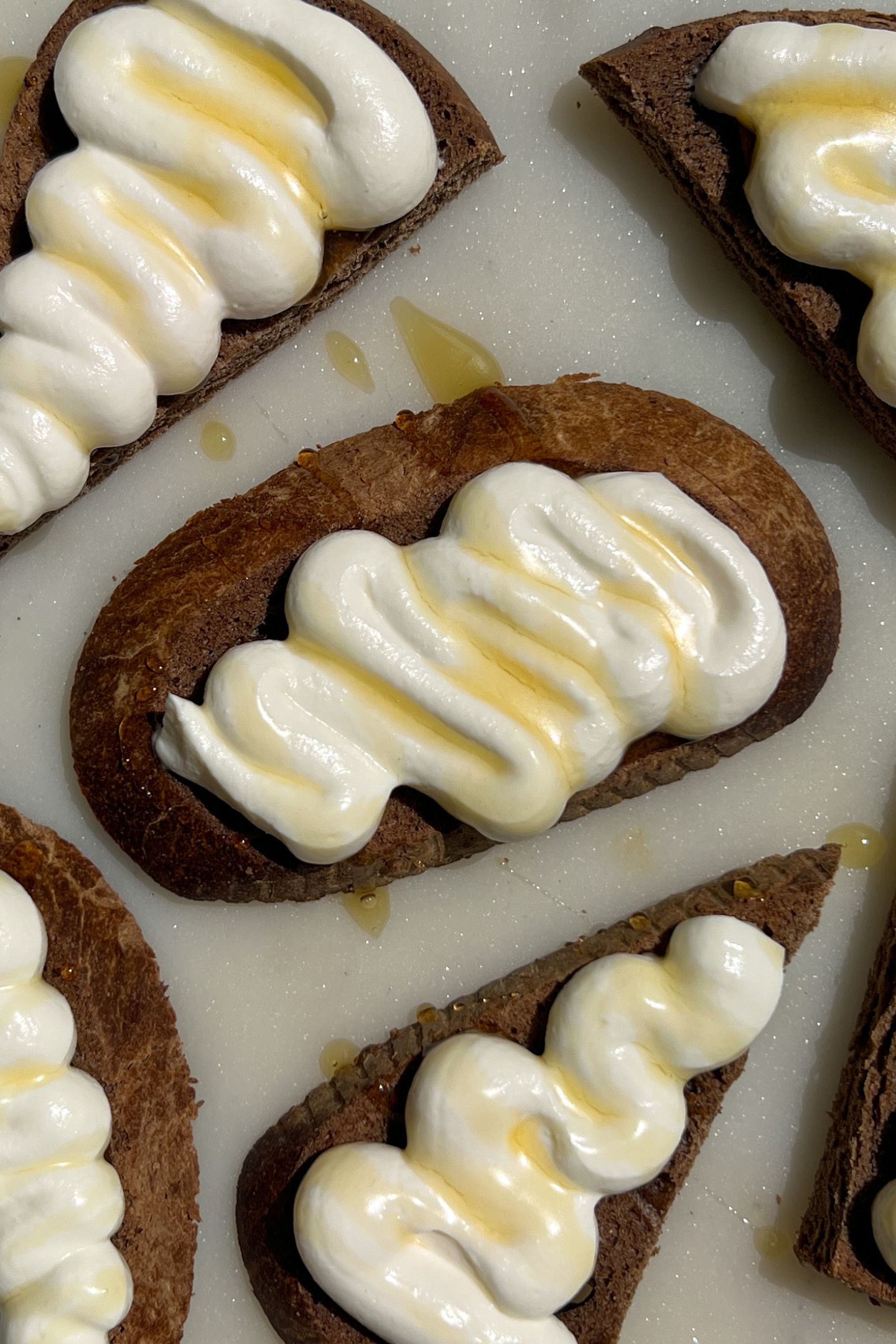 Crostini on a serving platter topped with goat cheese and honey.